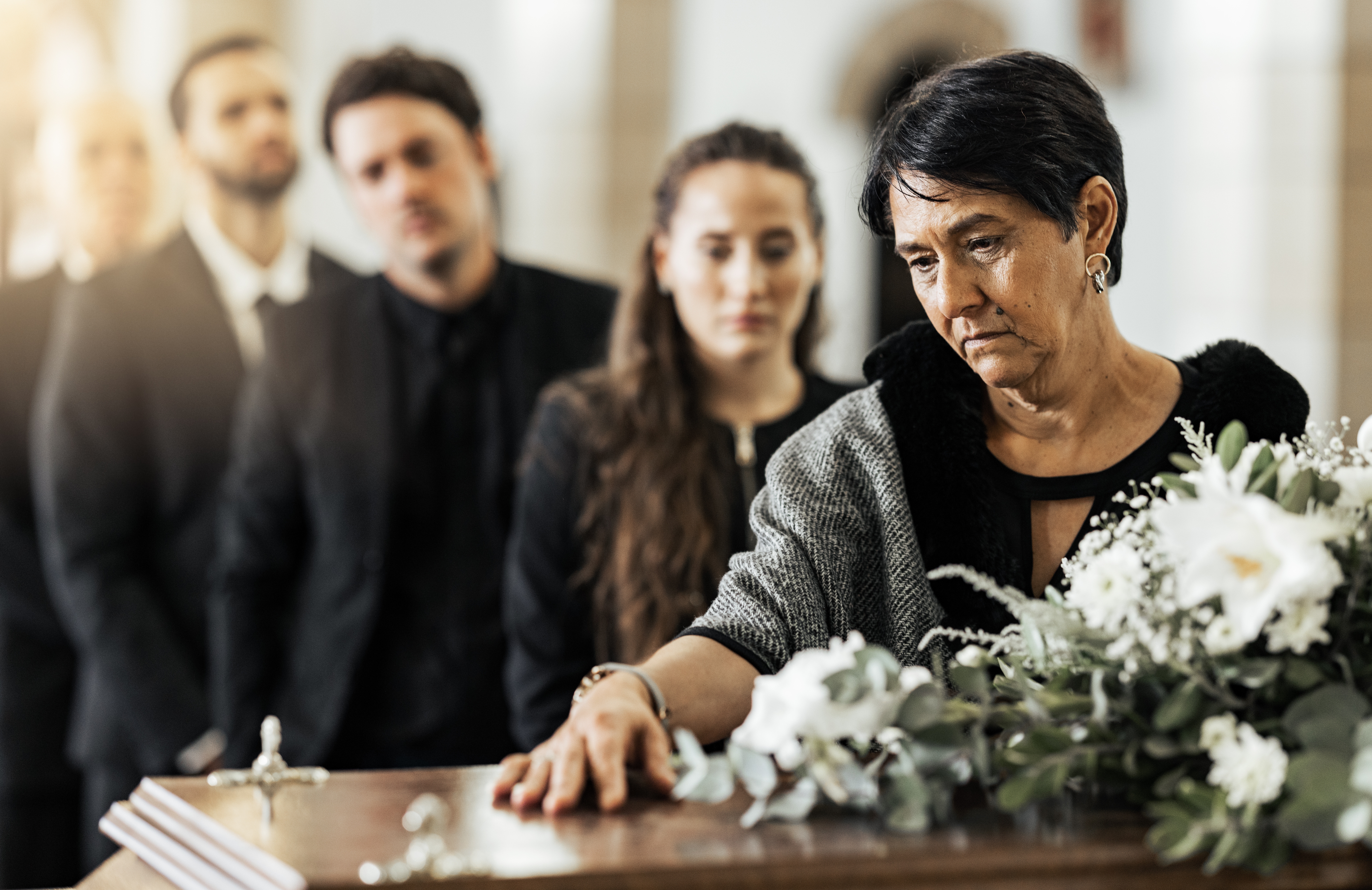 A woman placing her hand on the coffin during a funeral service | Source: Shutterstock