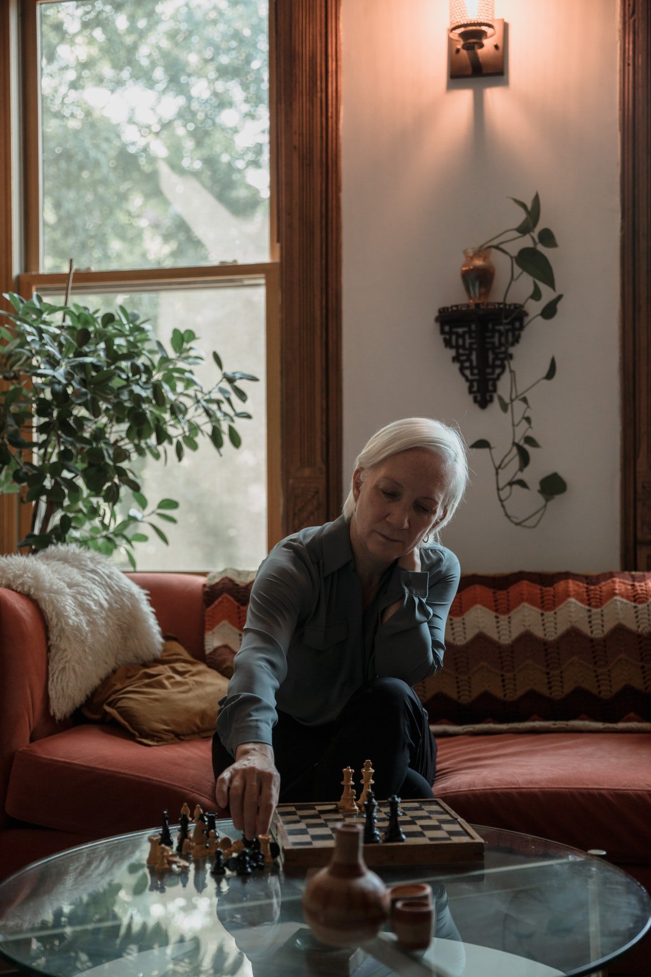Photo of an old woman playing chess while sitting on a couch | Photo: Pexels