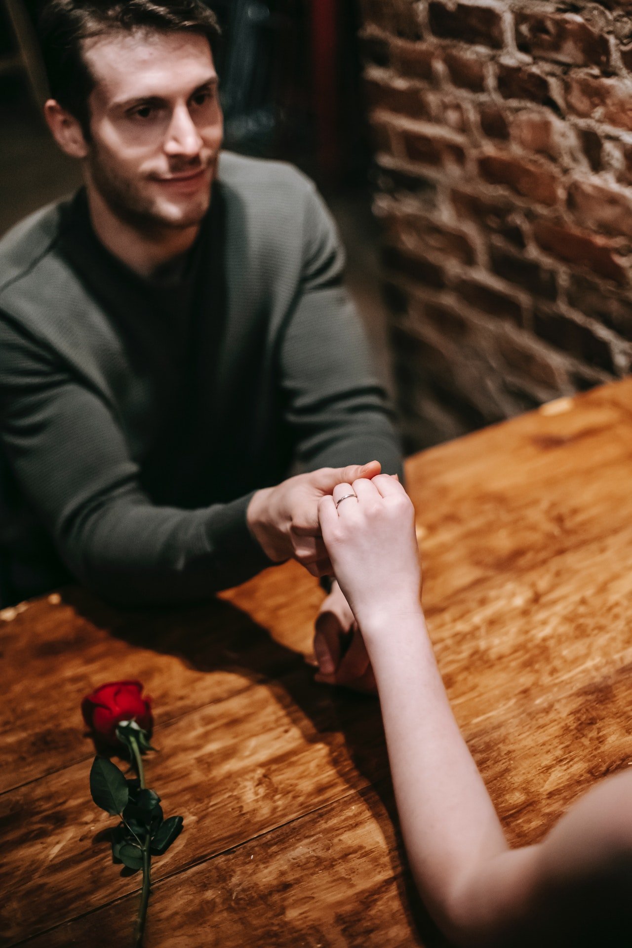 Un hombre joven toma la mano de su pareja por encima de la mesa. | Foto: Pexels