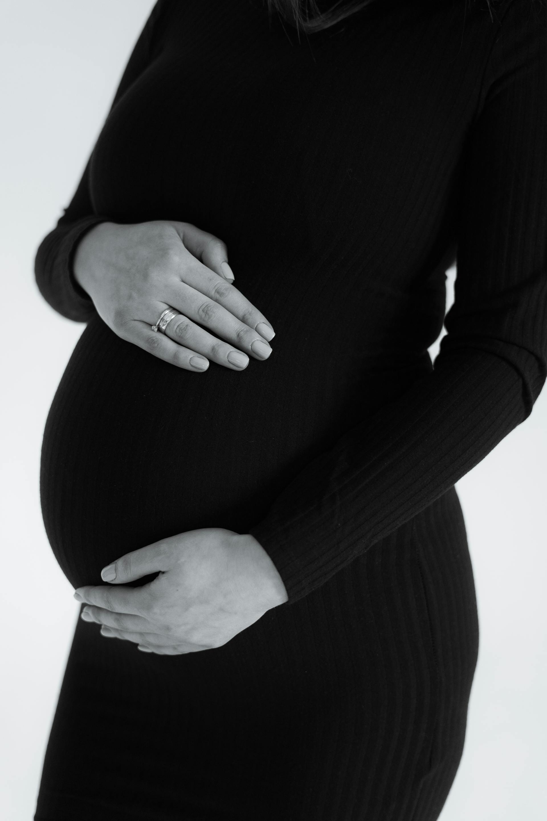 Grayscale photo of a woman holding her baby bump | Source: Pexels