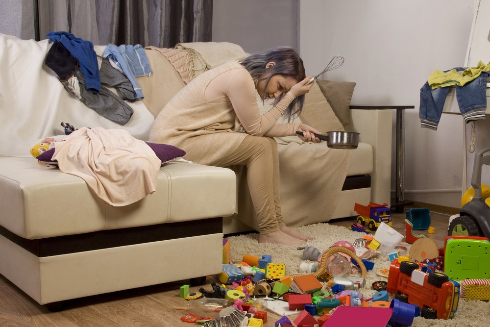 Madre cansada de ordenar la casa sentada en el sofá. Fuente: Shutterstock Madre cansada de ordenar la casa sentada en el sofá. Fuente: Shutterstock