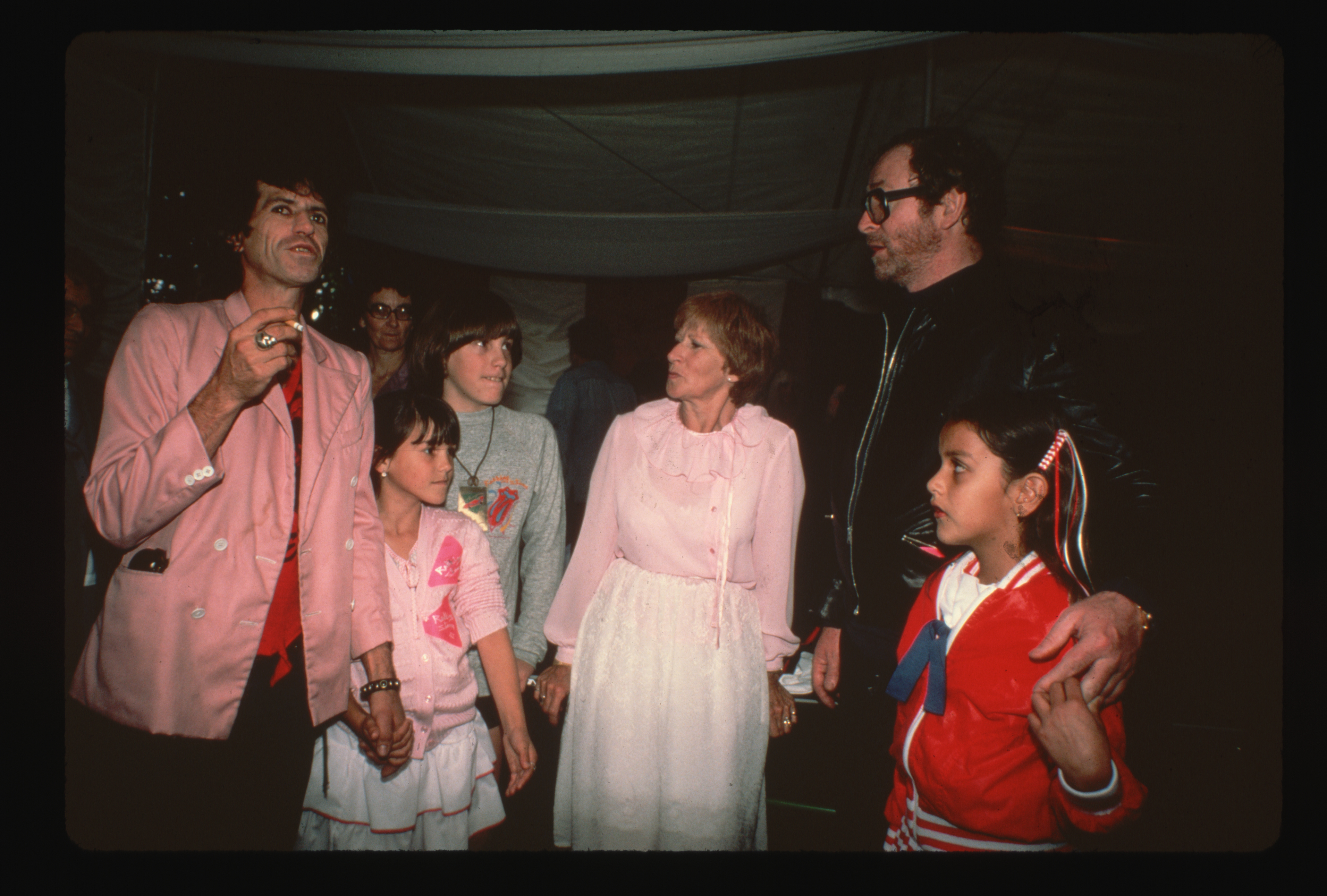 Michael Caine and Natasha pose and chat in 1982 with friends, including Rolling Stones guitarist Keith Richards, who holds his daughter Angela's hand. Also pictured are Richards' son Marlon and mother Doris, as the group enjoys a lively moment together.