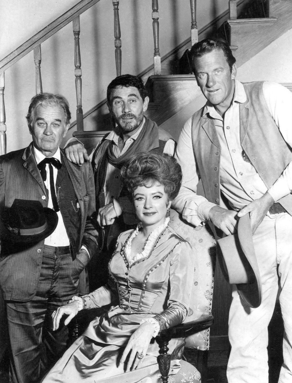 James Arness as Marshall Matt Dillon, Ken Curtis as Festus Hagen, and Milburn Stone as "Doc" Adams. Seated: Amanda Blake as "Miss Kitty" Russell in "Gunsmoke" in 1967. | Source: Wikimedia Commons.