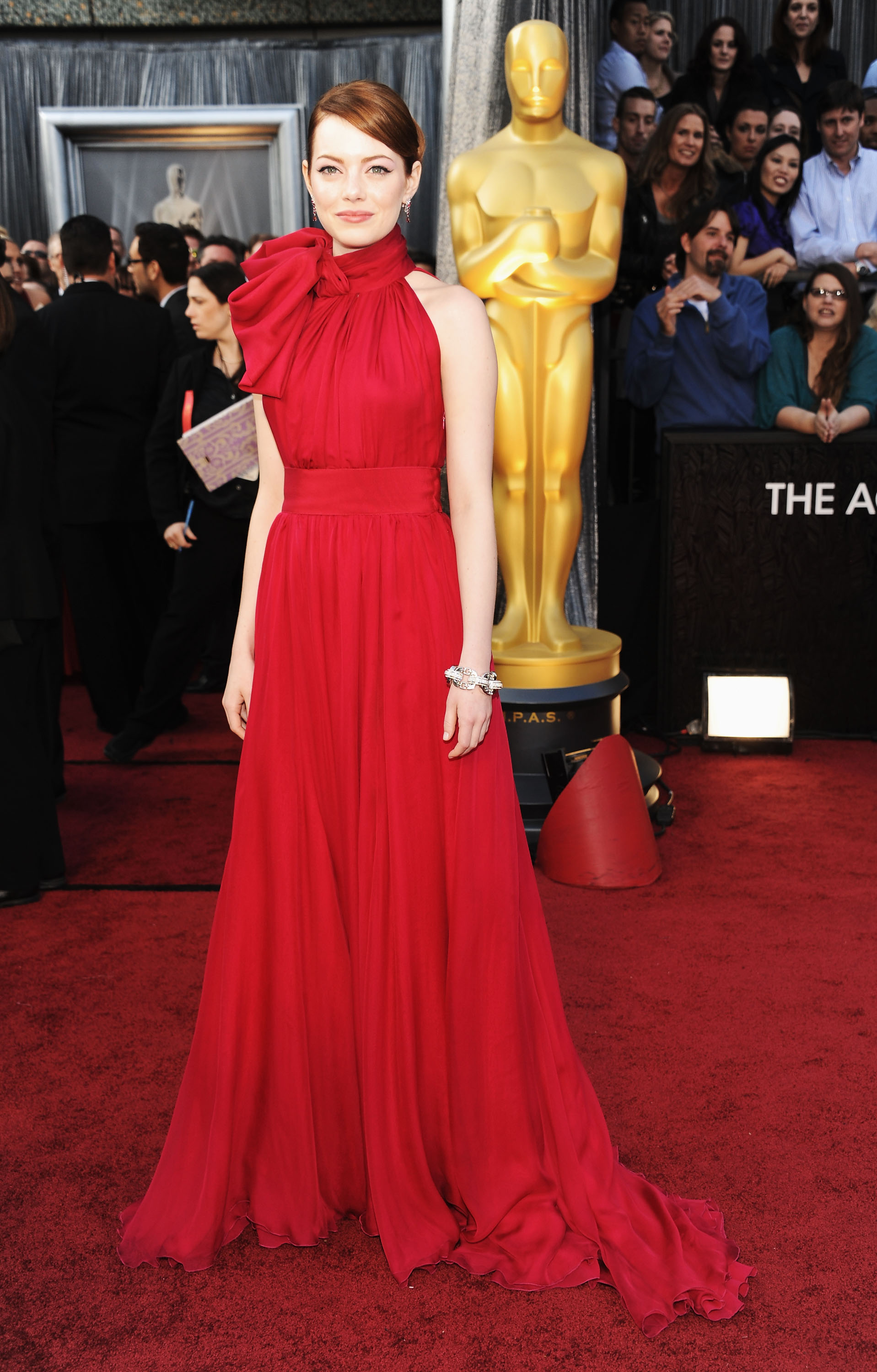 At the 84th Annual Academy Awards, the “La La Land” actress turned heads in a crimson gown featuring a dramatic bow detail at the neckline and a flowing chiffon skirt. She wore her hair in a sleek side-parted updo and kept the focus on her bold eyeliner and sparkling diamond accessories.