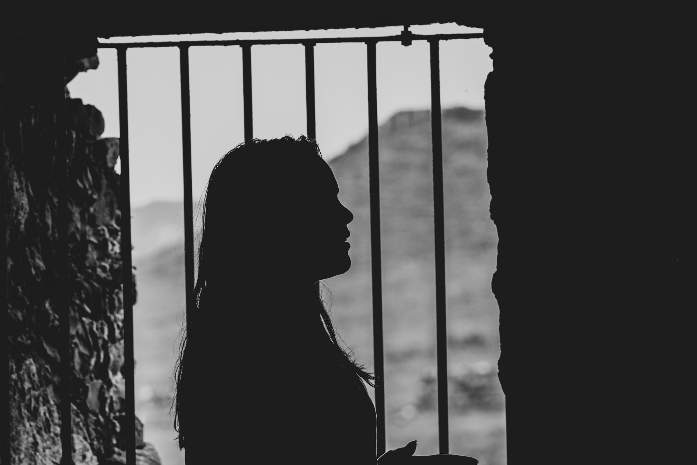 A woman's silhouette by the metal bar window | Source: Unsplash
