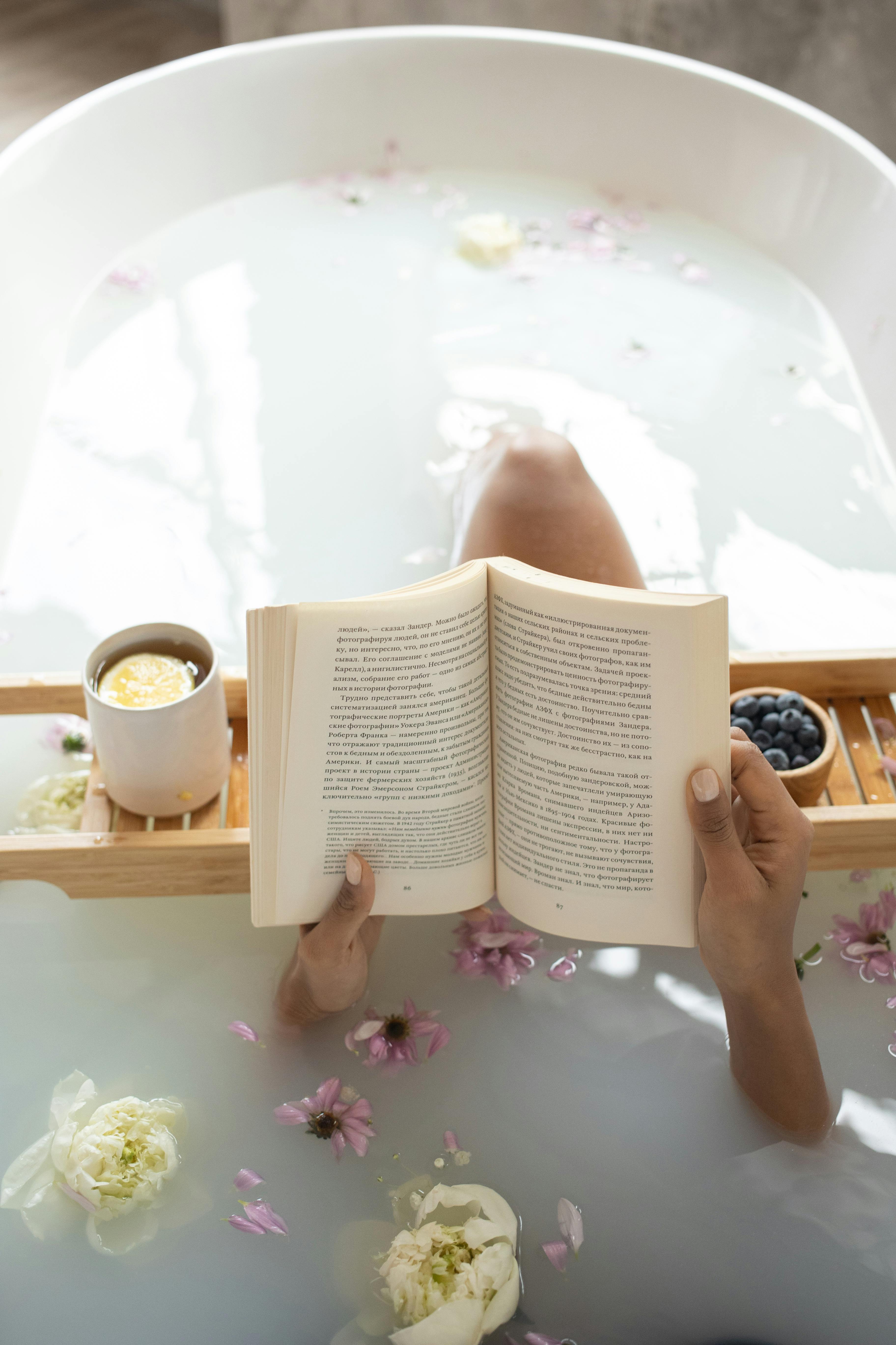 Uma mulher lendo um livro em uma banheira durante um tratamento de spa | Fonte: Pexels