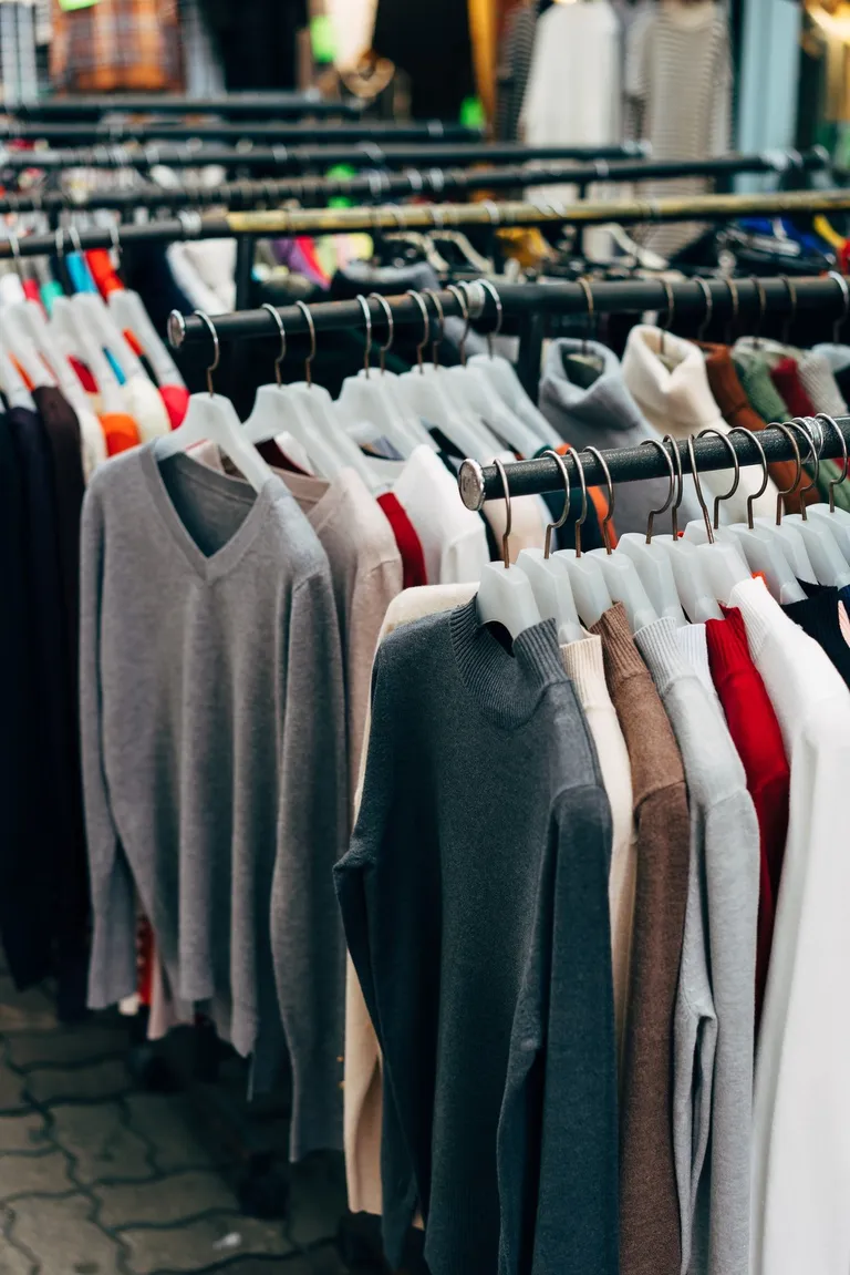 Des pulls suspendus à des portants | Source : Pexels