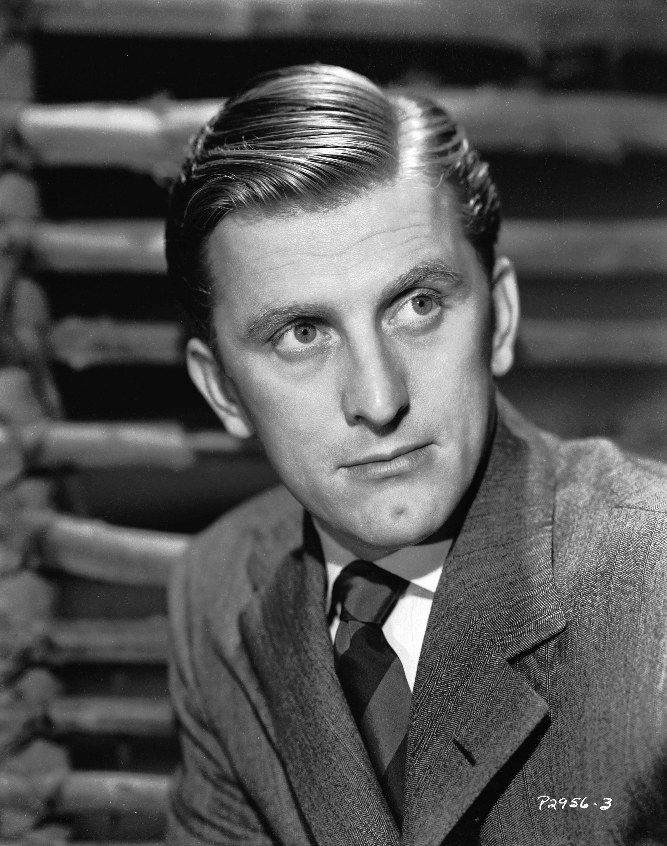 Pictured: A head-shot of Hollywood filmmaker and veteran star Kirk Douglas wearing a blazer with paired with a white shirt and a striped tie in 1945. | Source: Getty Images