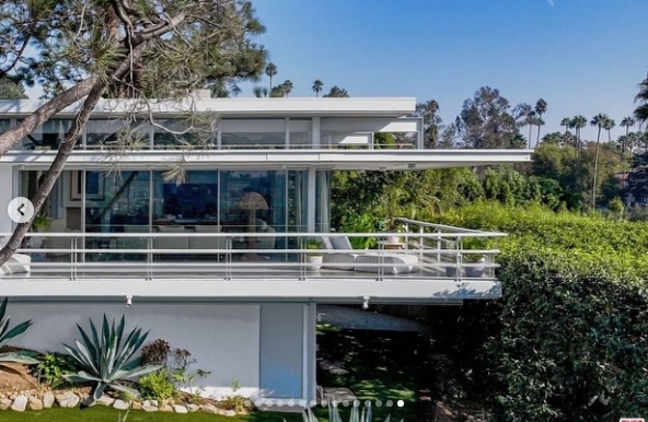 From the exterior, the residence's midcentury architecture comes fully into view, with long horizontal lines, broad panes of glass, and a wraparound terrace projecting over the landscaped grounds. Mature trees and hedges surround the structure, giving the hillside property privacy while preserving its open, light-oriented design. | Source: Instagram/jparkerstanton