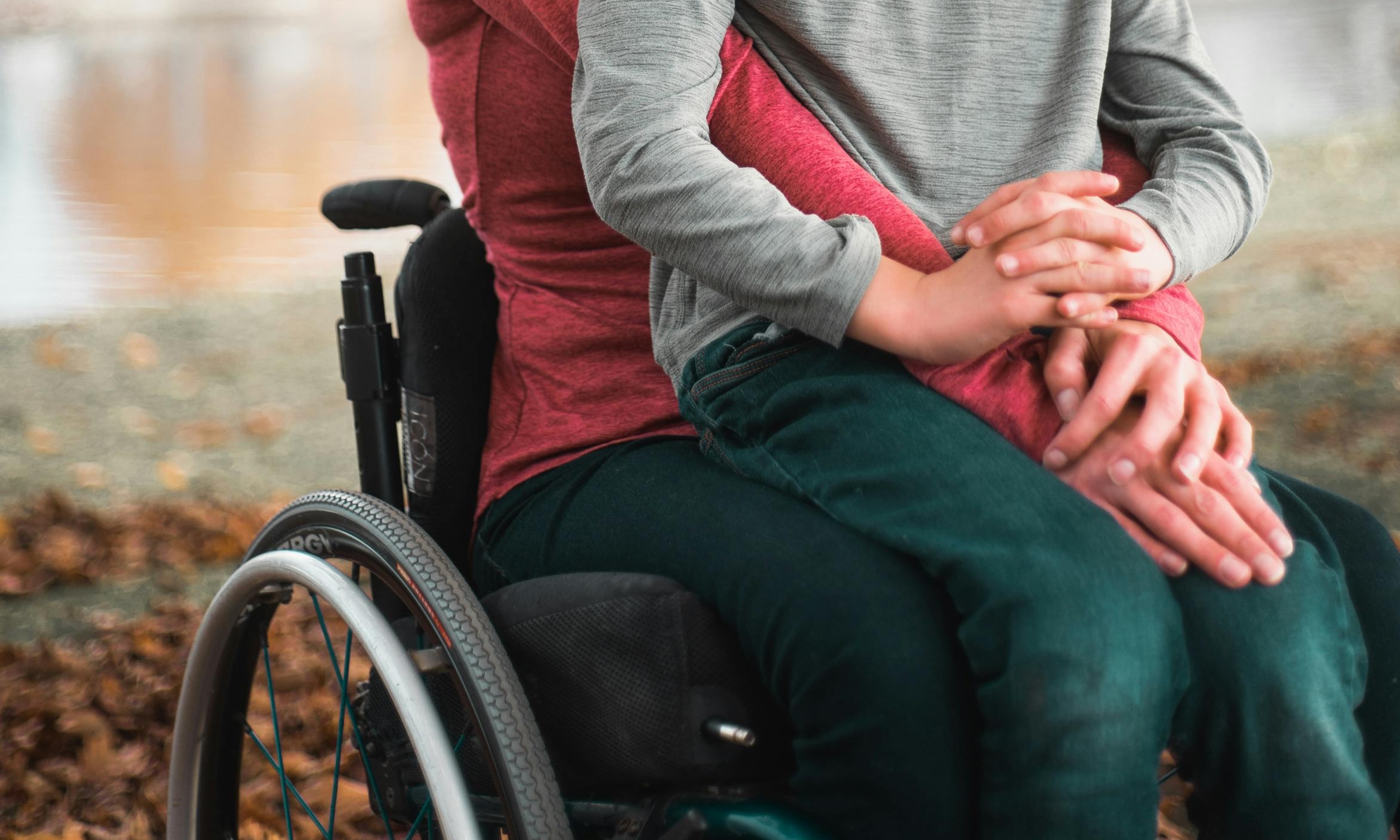 A woman and boy sit together in a wheelchair | Source: Pexels