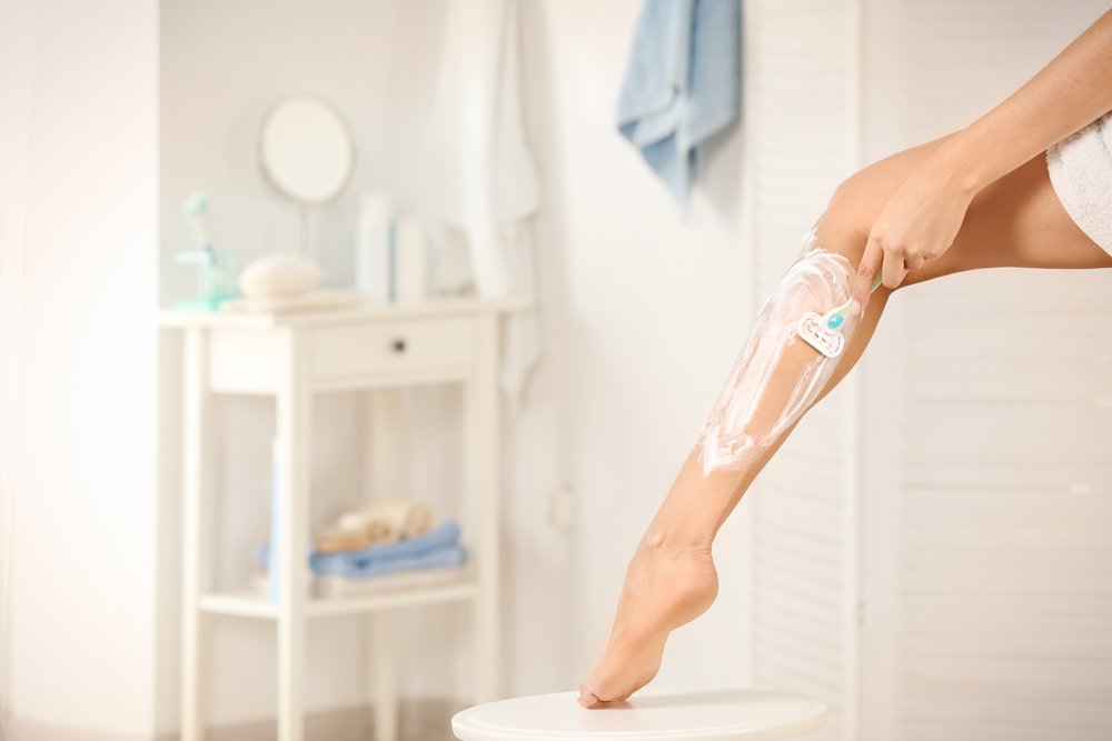 A photo of woman shaving her leg in bathroom. | Photo: Shutterstock.