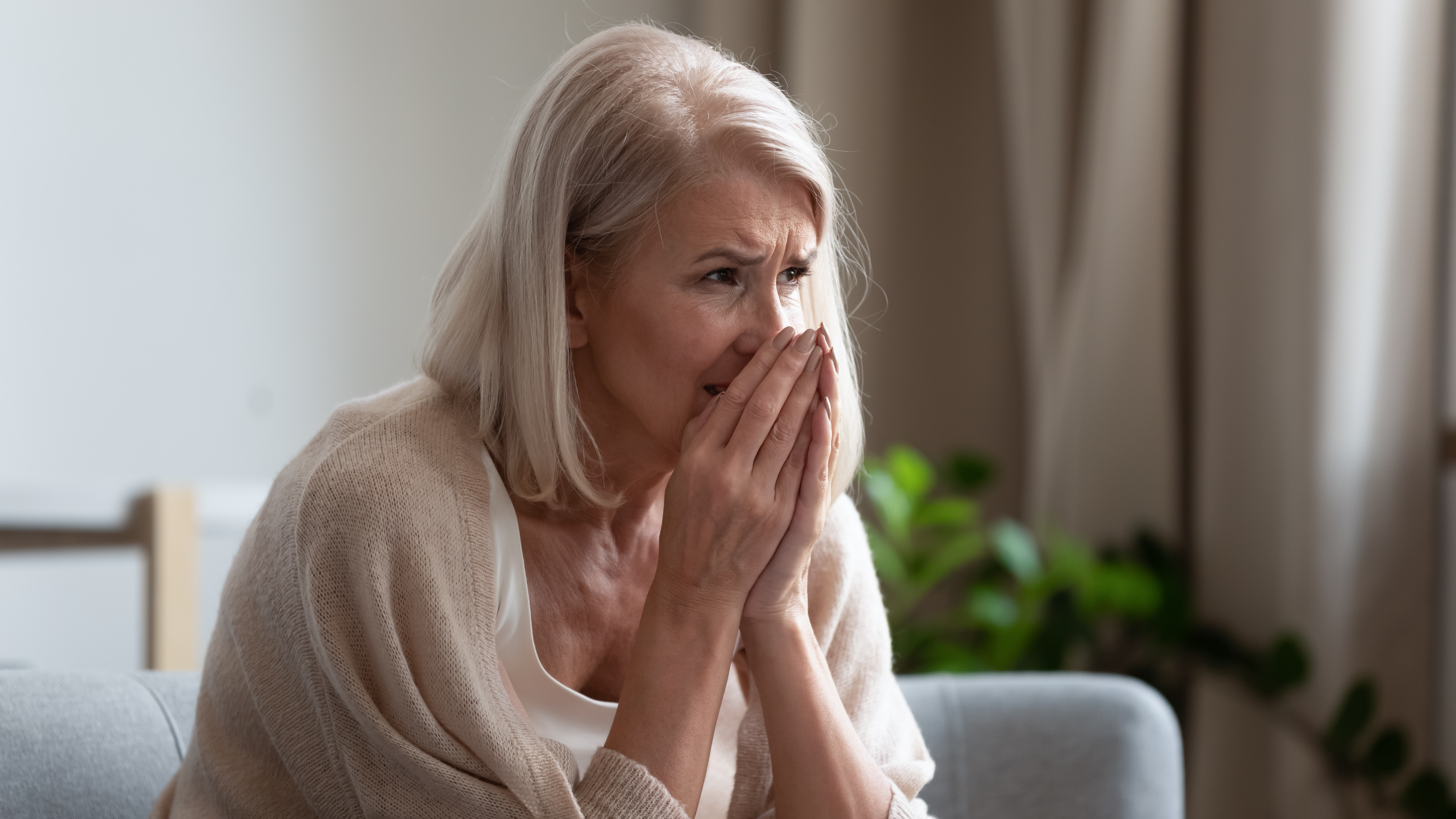 Worried senior woman sitting on a couch | Source: Shutterstock