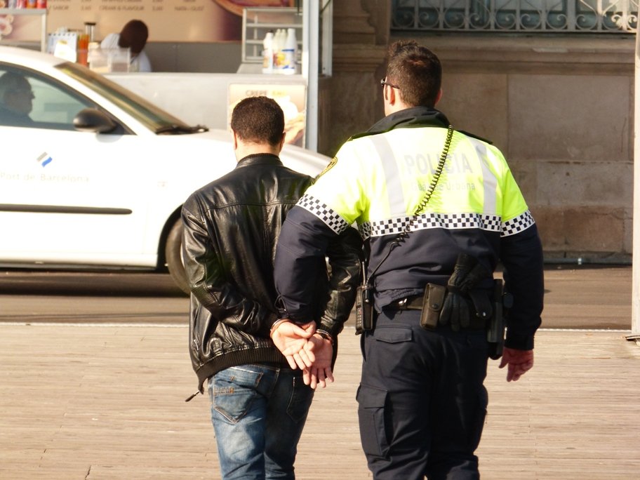 Policía trasladando a un hombre esposado. | Imagen: Flickr