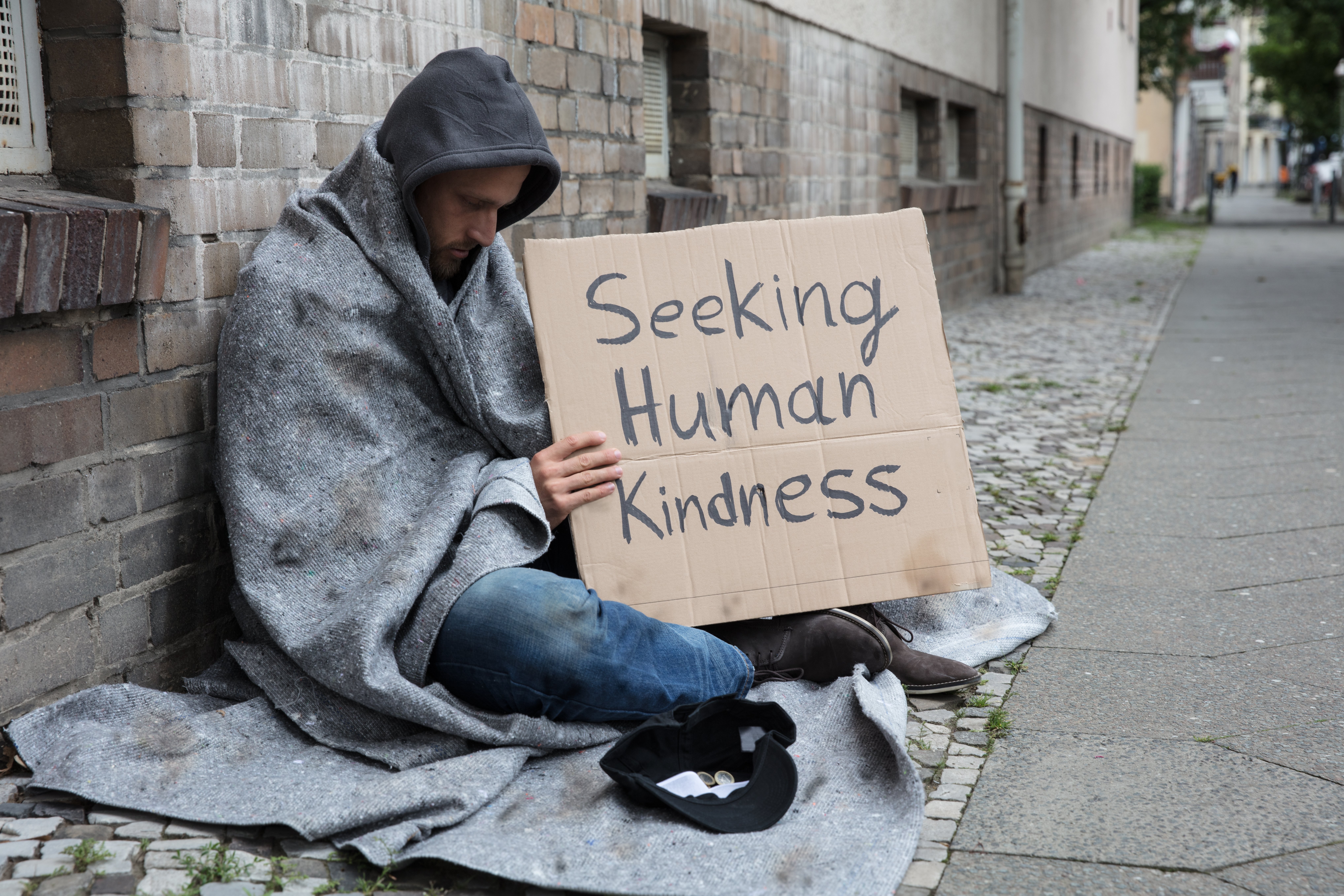 Un sans-abri qui tient un pancart "à la recherche de la bonté humaine" | photo : Shutterstock Un sans-abri qui tient un pancart "à la recherche de la bonté humaine" | photo : Shutterstock