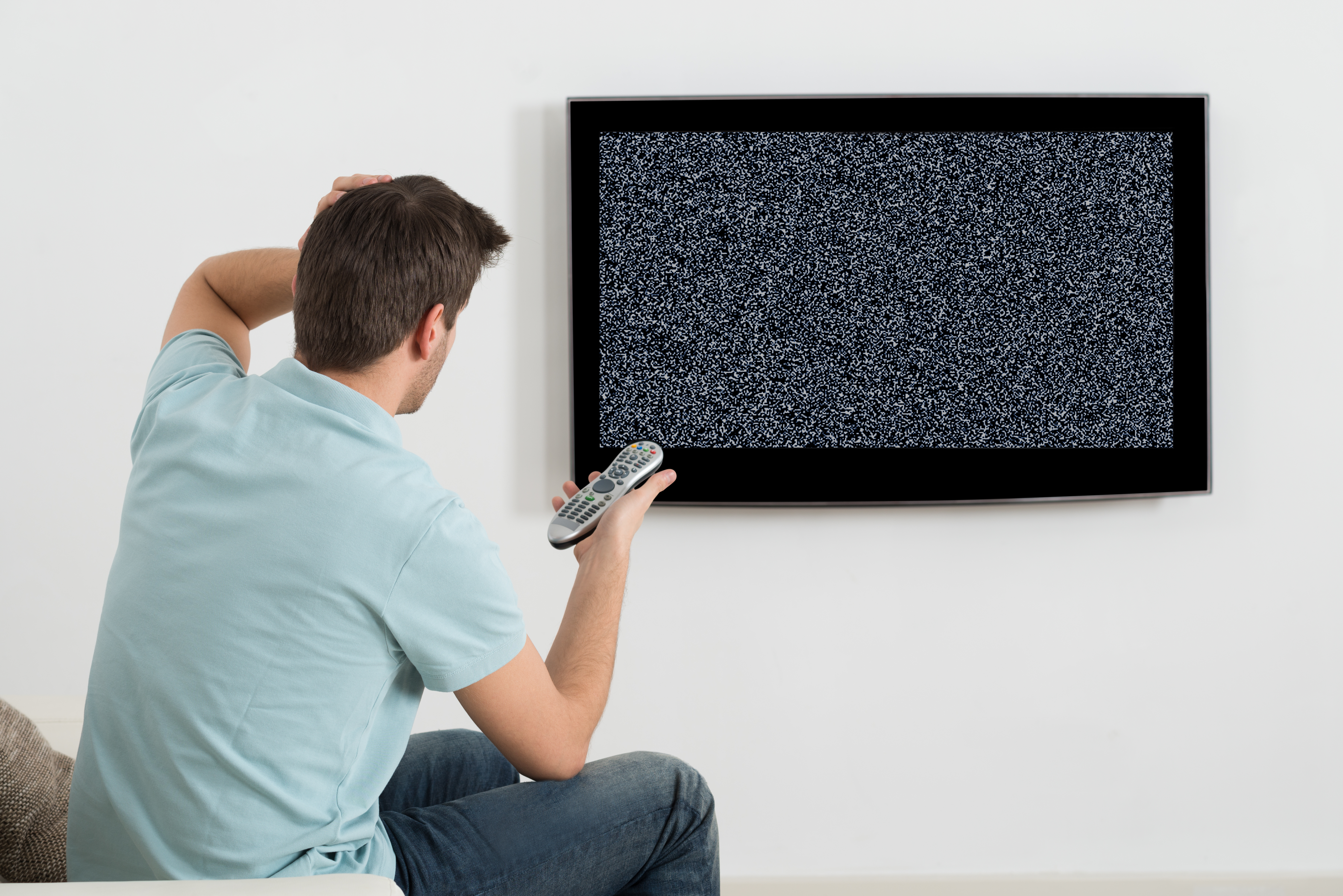 A confused man trying to turn on a TV | Source: Shutterstock