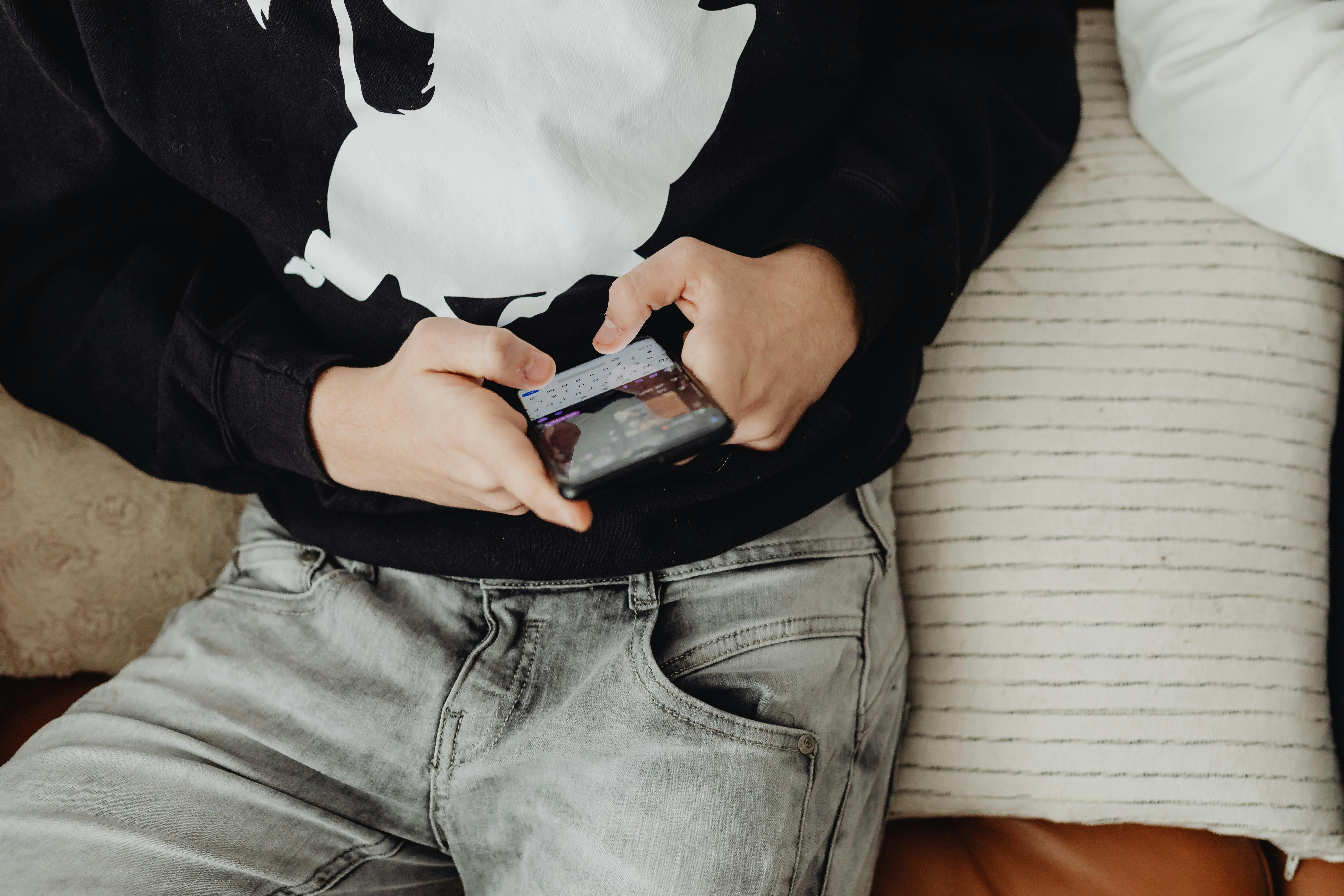 A boy using his phone while sitting | Source: Pexels