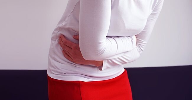 Une femme pliée en deux par la douleur. l Source : Shutterstock