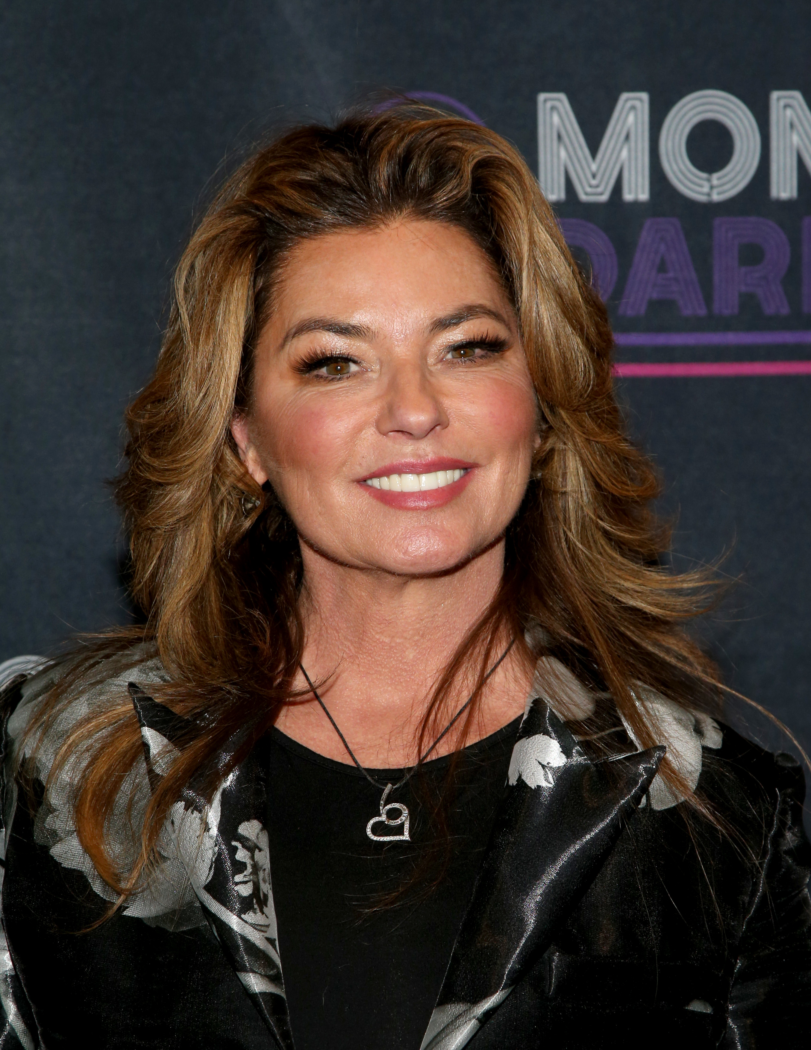 Attending a charity anniversary event in Las Vegas in late 2021, a smiling Shania Twain complemented her tailored floral outerwear with soft smoky eye makeup and her signature bouncy blowout. | Source: Getty Images