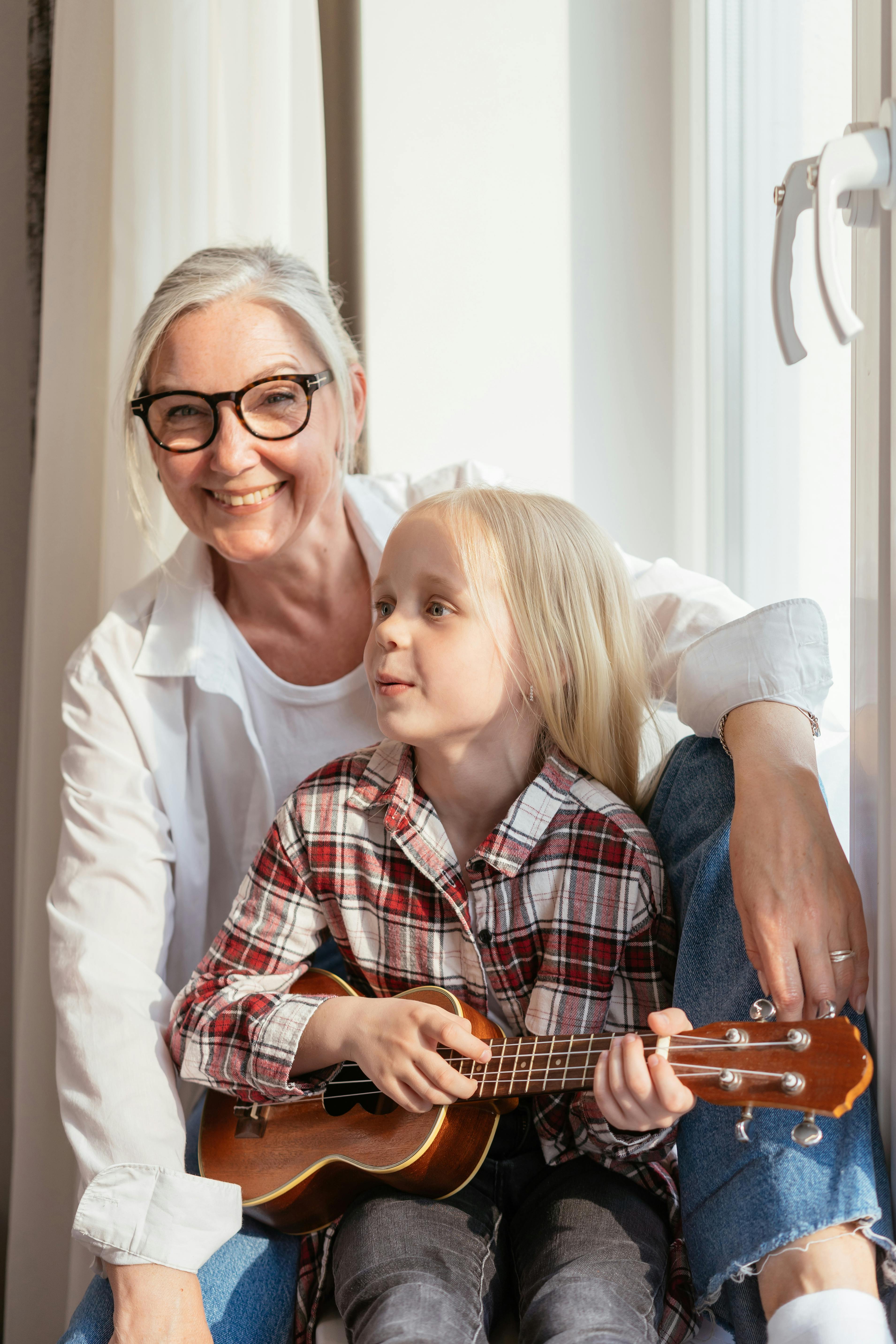 A woman bonding with a little girl holding a guitar | Source: Pexels