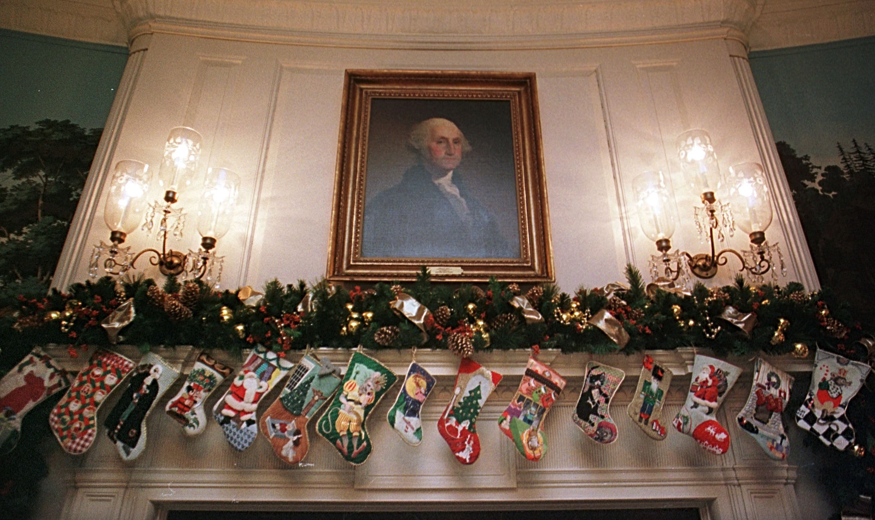 Christmas socks hang on the fireplace below a portrait of President George Washington in the Diplomatic Reception Room of the White House December 4, 2000 in Washington DC. | Source: Getty Images