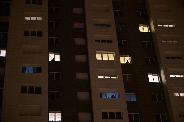 Des personnes observent depuis leurs fenêtres les patrouilles de police dans les rues.| Photo : Getty Images