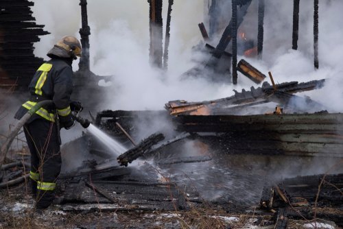 Fireman spraying water in a smouldering burnt out house.| Photo: Shutterstock.