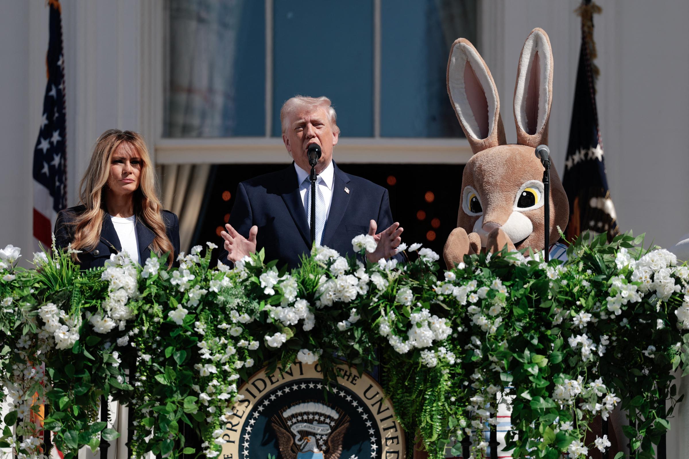 Donald Trump addresses the crowd gathered for the celebratory event as Melania Trump and the Easter Bunny stand on either side of him.