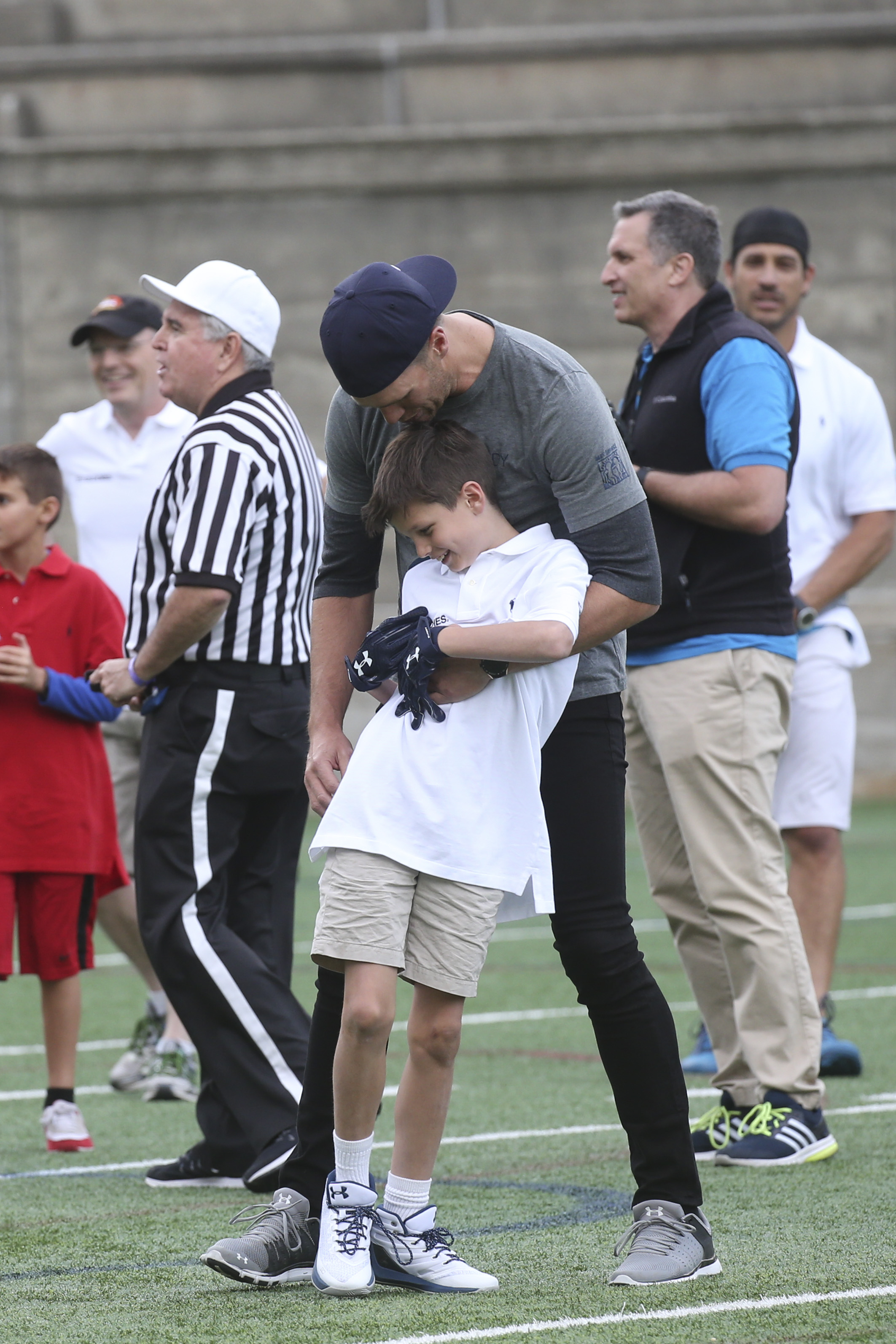 Tom Brady embraces Jack Moynahan on the field during the Best Buddies Challenge at Harvard Stadium, showcasing their close bond at the annual charity event.