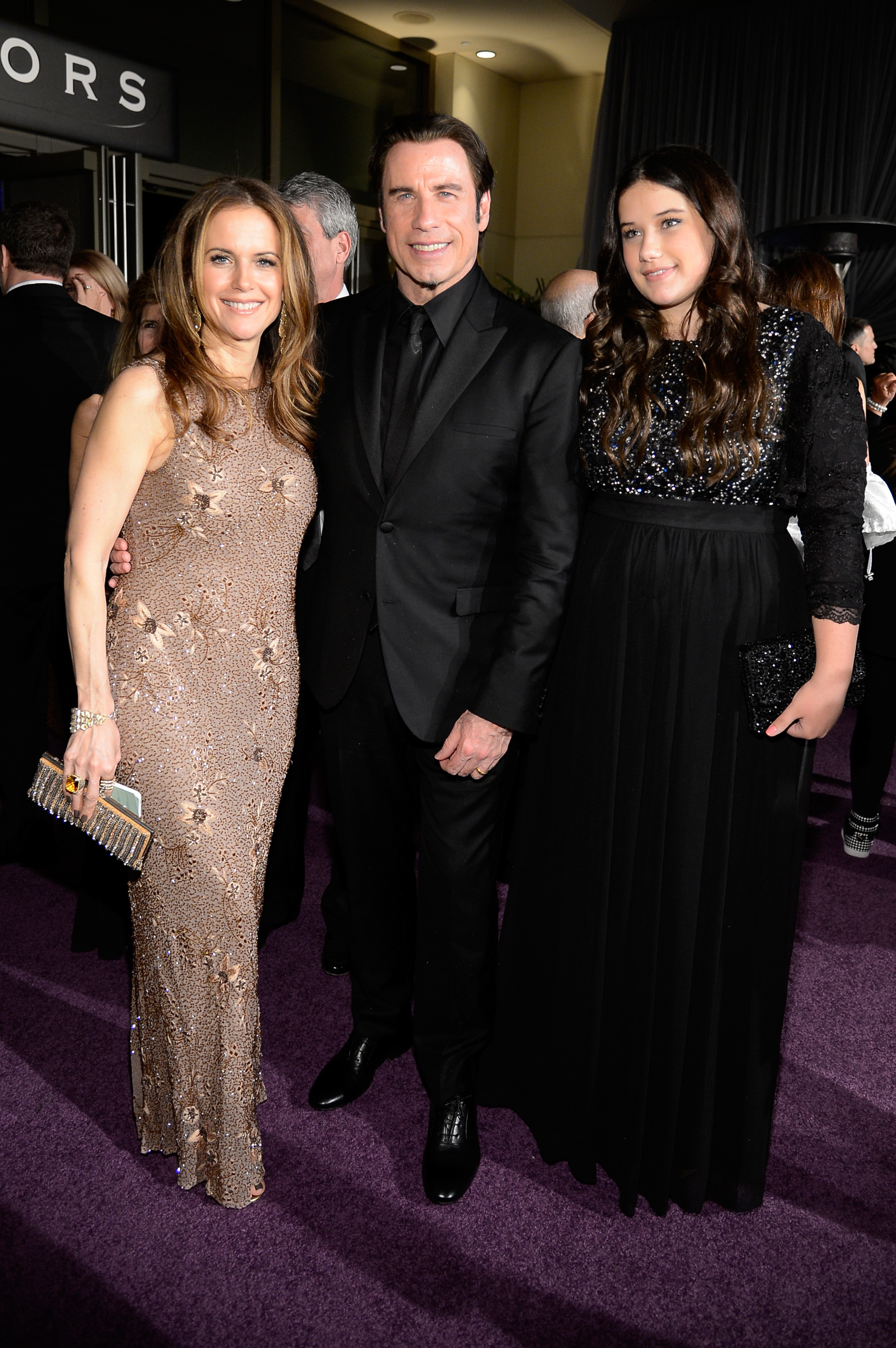 Kelly Preston, John Travolta, and Ella Bleu Travolta pose together at the 2013 Oscars Governors Ball. Ella wears a long black gown, standing beside her parents as the family attends one of Hollywood's biggest nights.
