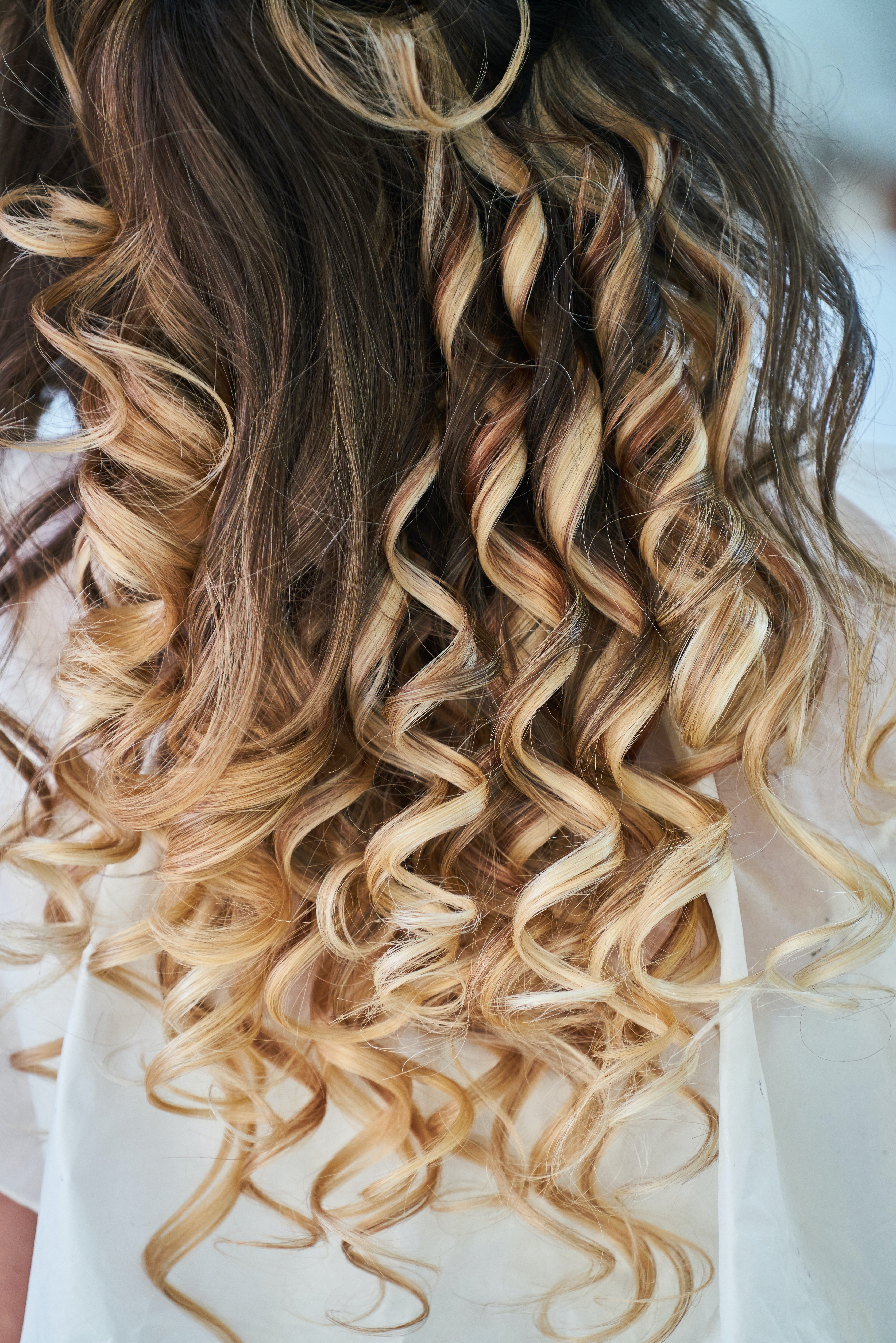 Une coupe de cheveux bouclés avec des mèches blonde 