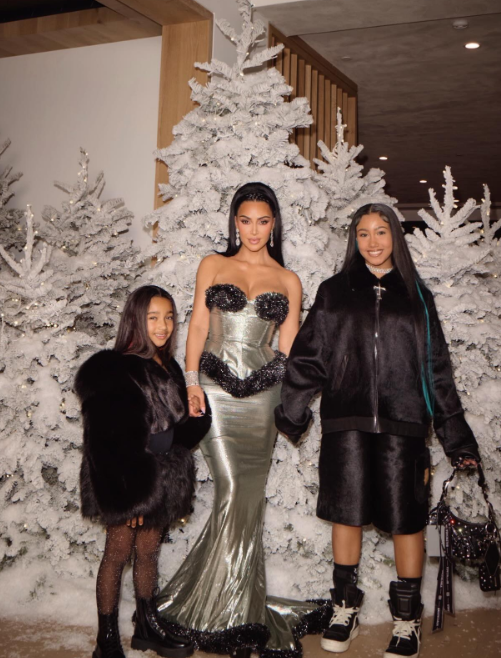 Kim Kardashian and her daughters North and Chicago West posing in front of Christmas trees, from a post dated December 27, 2025 | Source: Instagram/kimkardashian