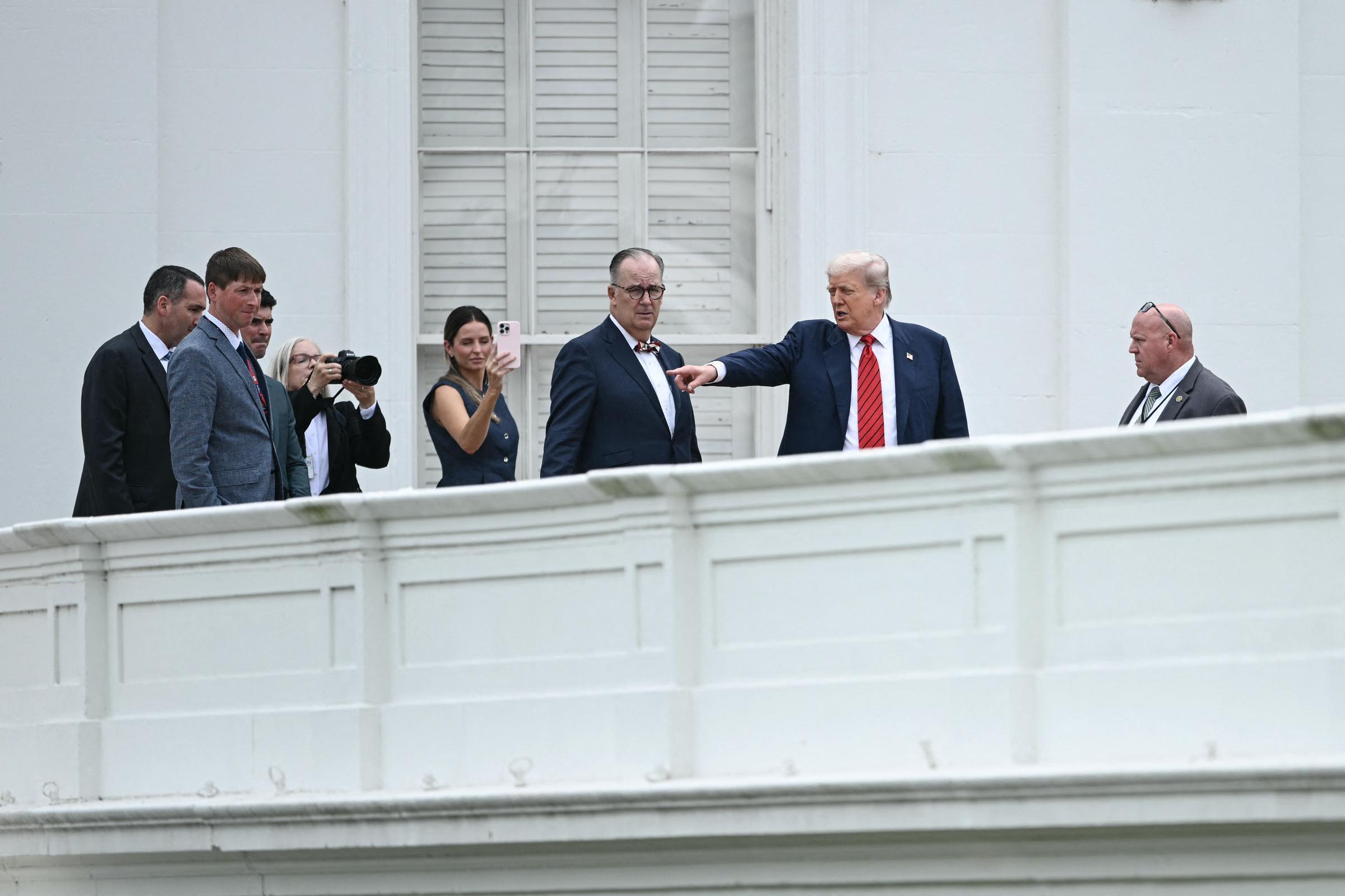 Accompanied by architect James C. McCrery and aides, Donald Trump points across the White House roof during his rooftop tour, highlighting areas slated for renovation as cameras capture the rare scene.