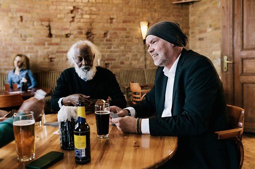 A group of older gentlemen talking drinking together at a bar | Photo: Getty Images