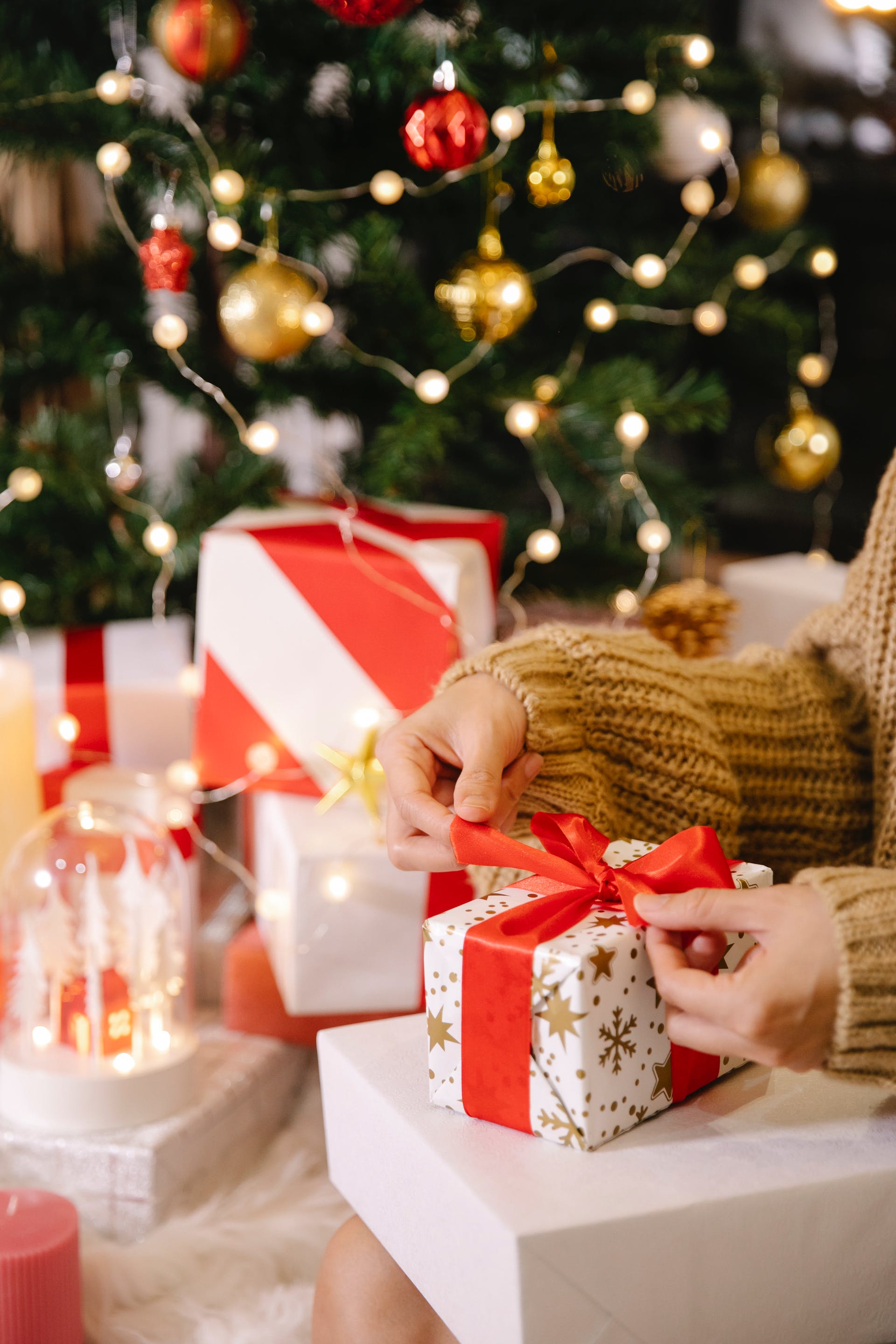 Woman wrapping a gift box near a Christmas tree | Source: Pexels