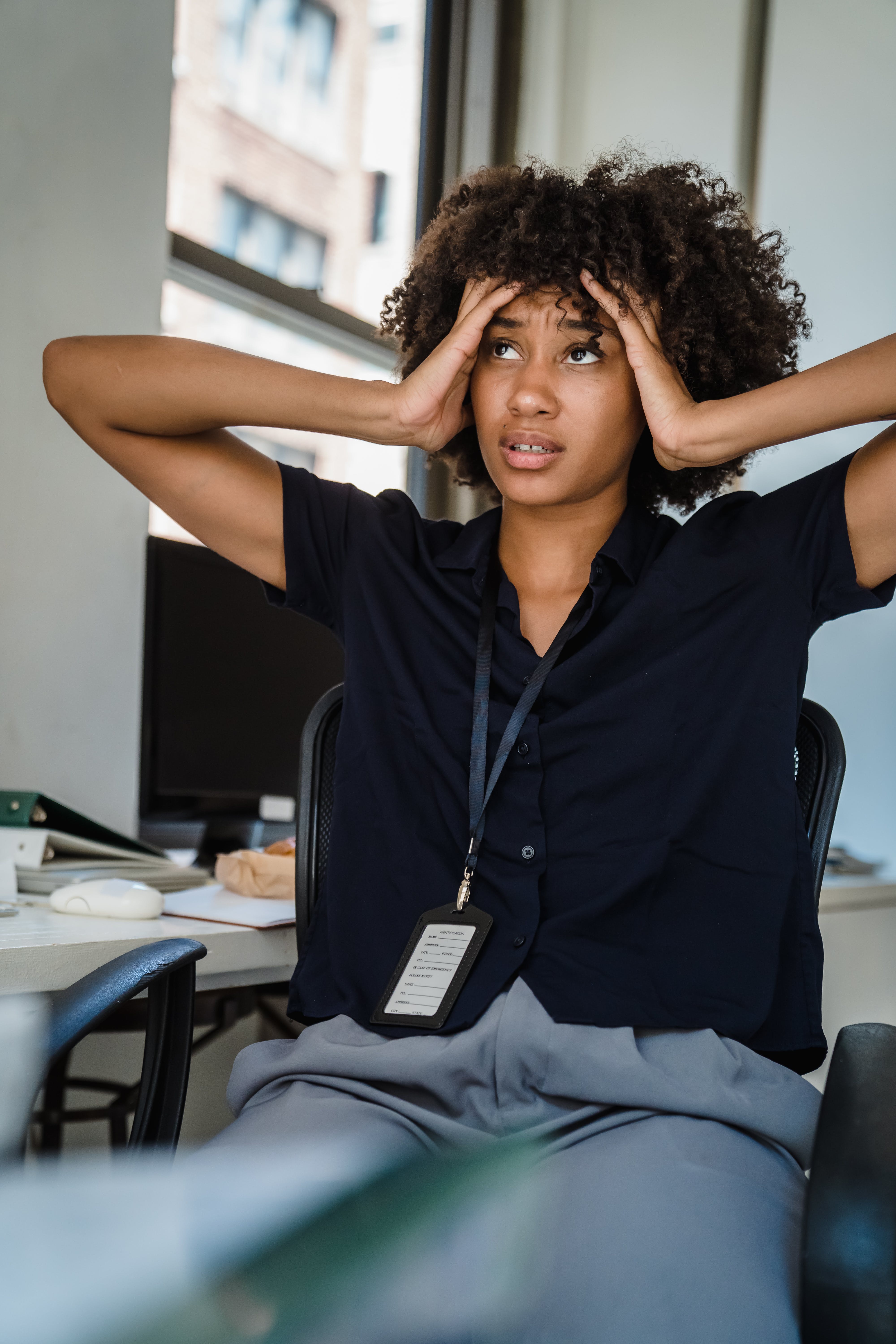 A frustrated woman sitting down and holding her head while looking to the side | Source: Pexels