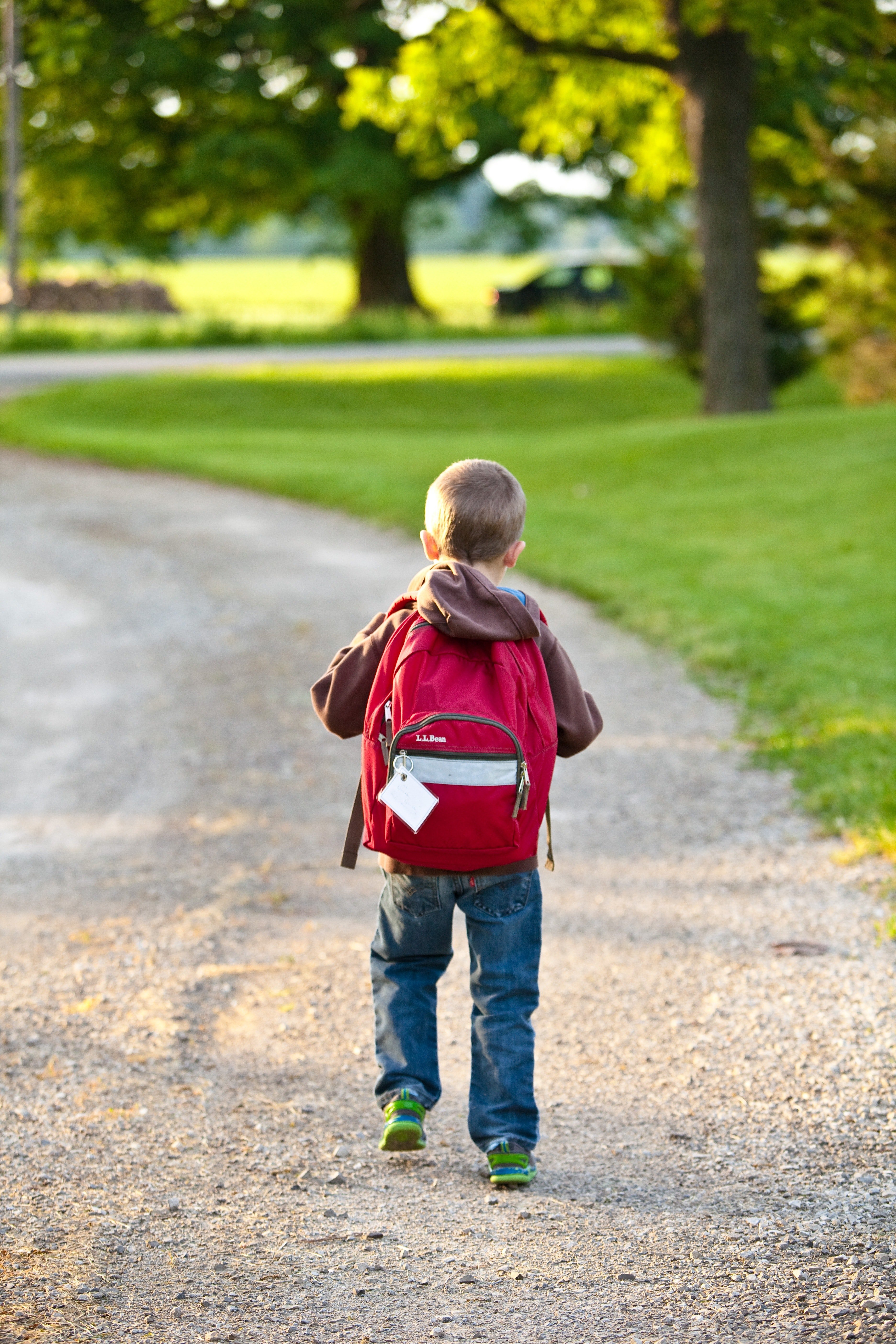 A young boy walking to school carrying his backpack. | Source: Pexels
