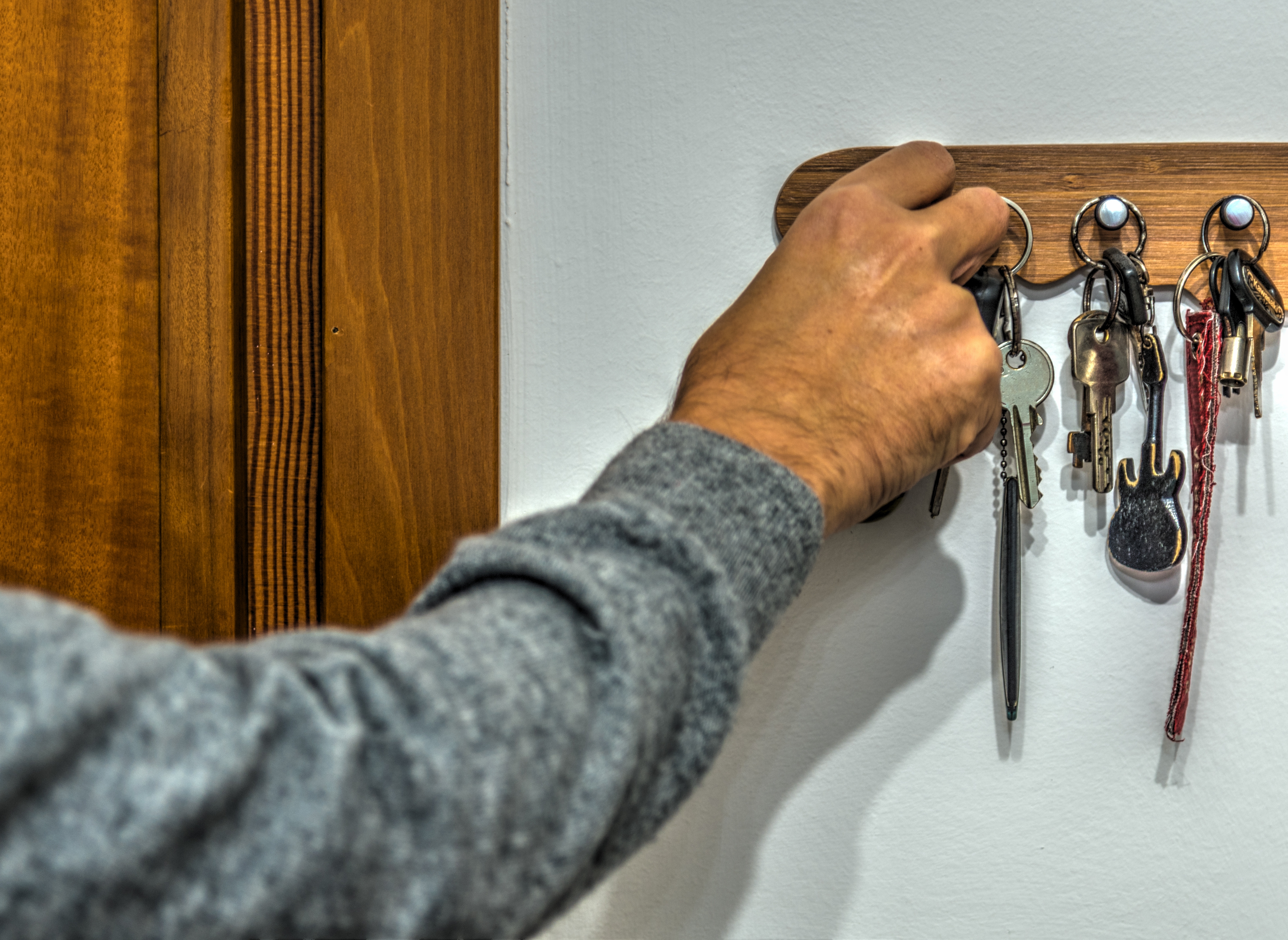 Close up of a man's hand grabbing a key from the key holder. | Source: Shutterstock