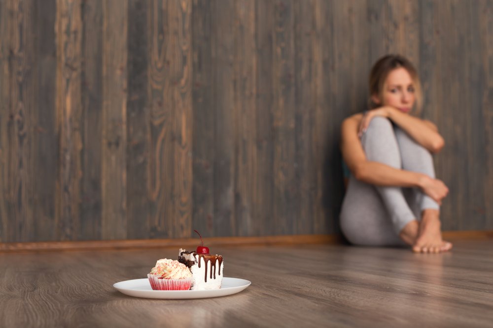 Mujer deprimida mirando fijamente las tortas. Fuente: Shutterstock