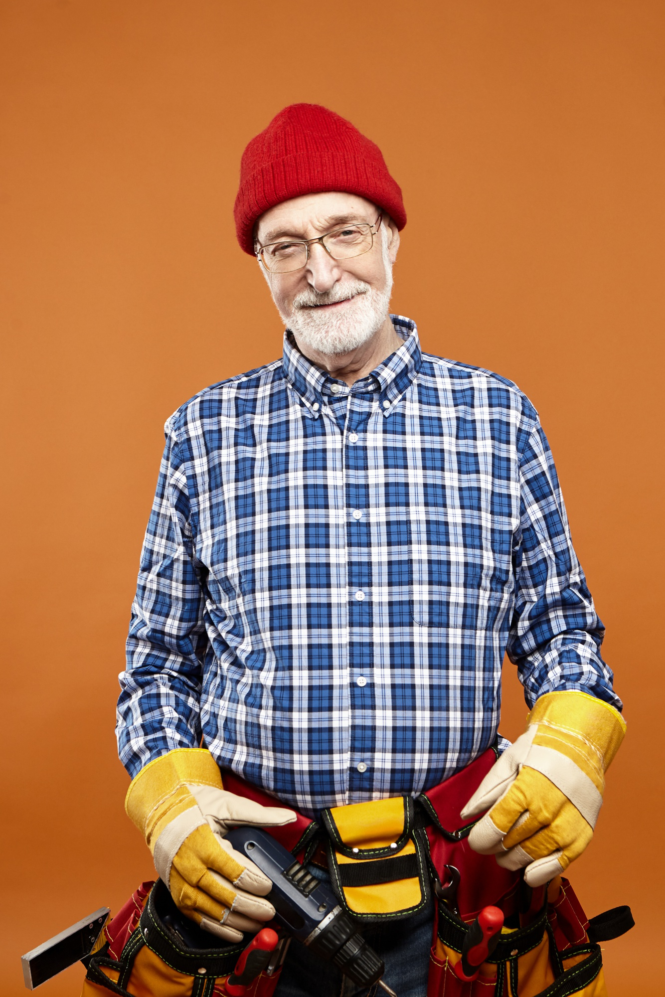 A happy middle-aged man wearing a toolbelt and holding tools | Source: Freepik