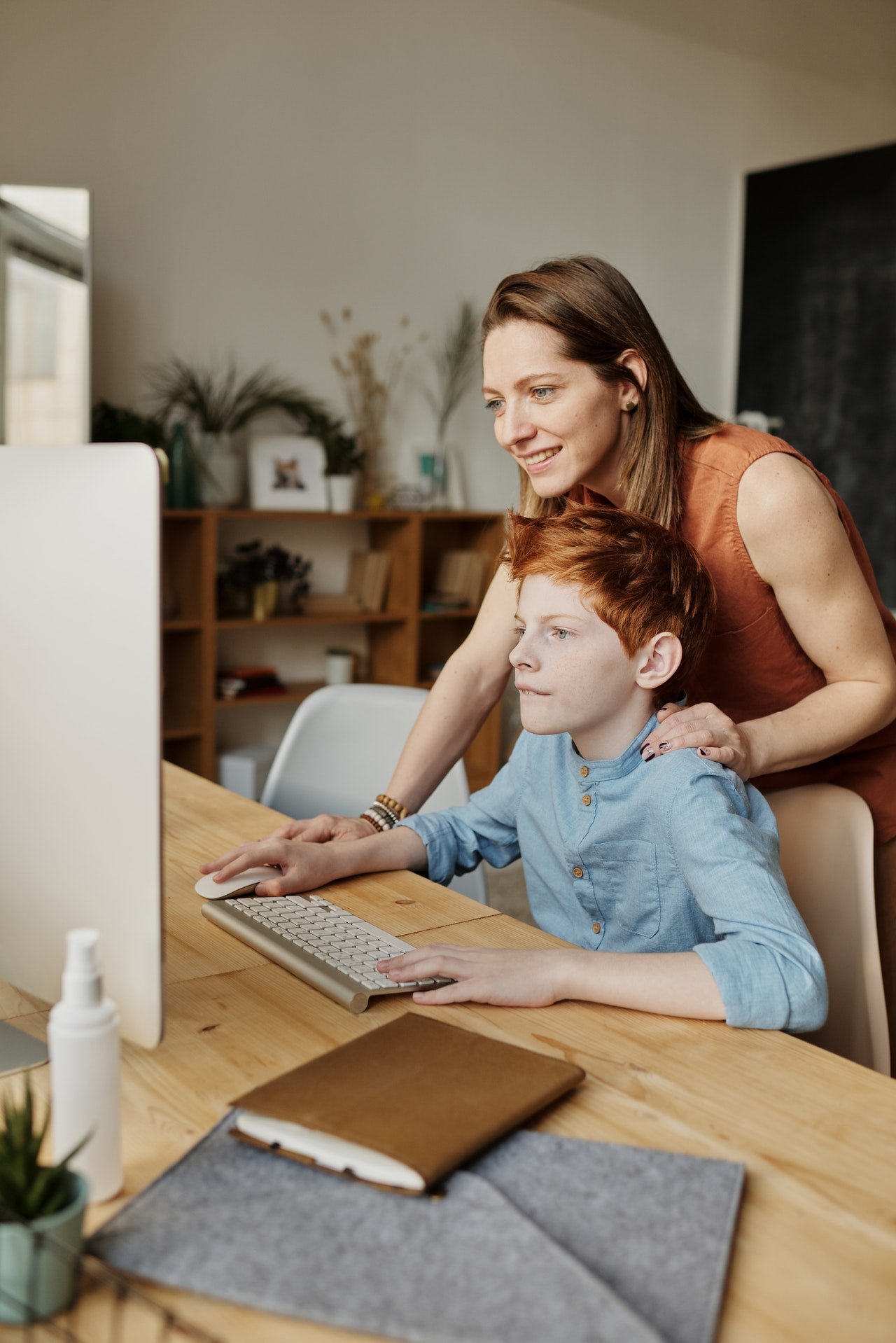 Mother helping her son out with the computer | Photo: Pexels