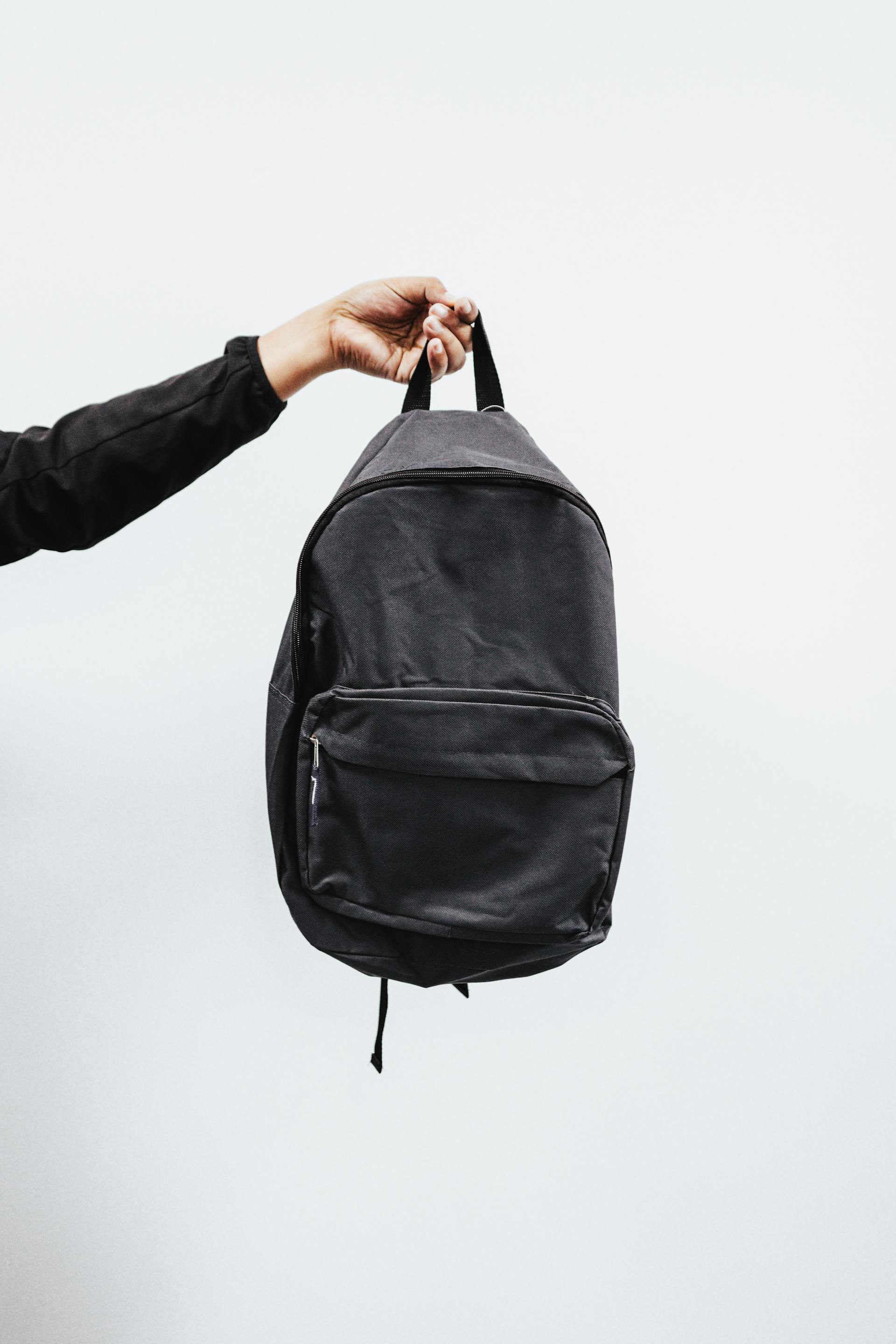 A person holding a black backpack | Source: Pexels