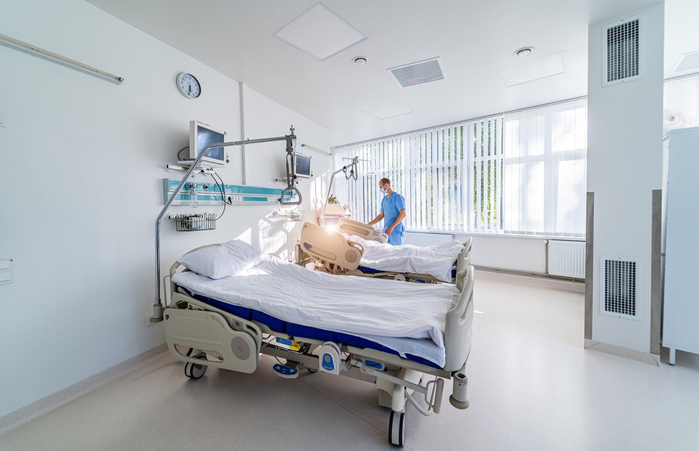 An intensive care unit at a hospital with a doctor checking on a patient's vitals who is lying on a bed | Photo: Shutterstock/Terelyuk