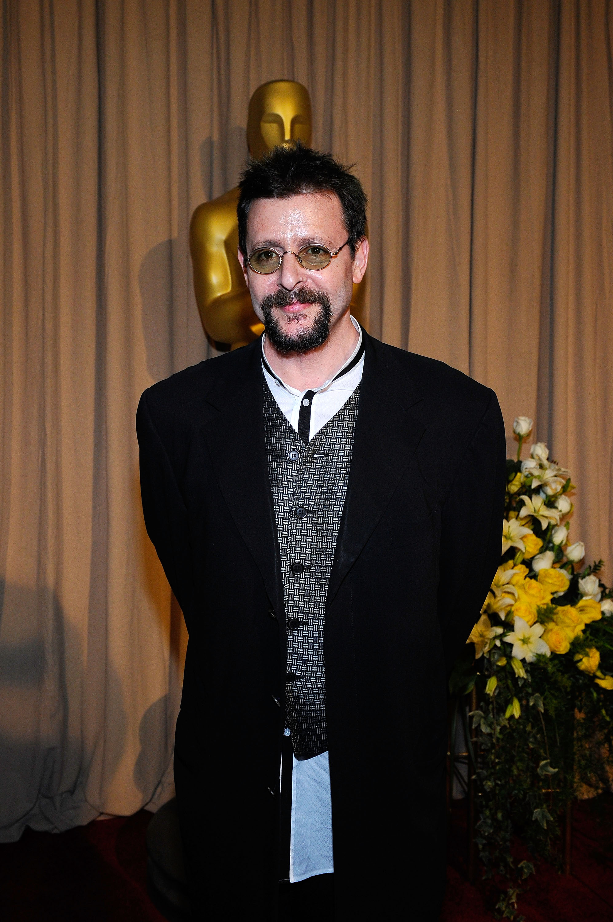 Posing backstage near a golden Oscar statuette at the 82nd Annual Academy Awards on March 7, 2010, the actor paired a patterned vest and dark coat with small tinted glasses and a neatly trimmed goatee. | Source: Getty Images
