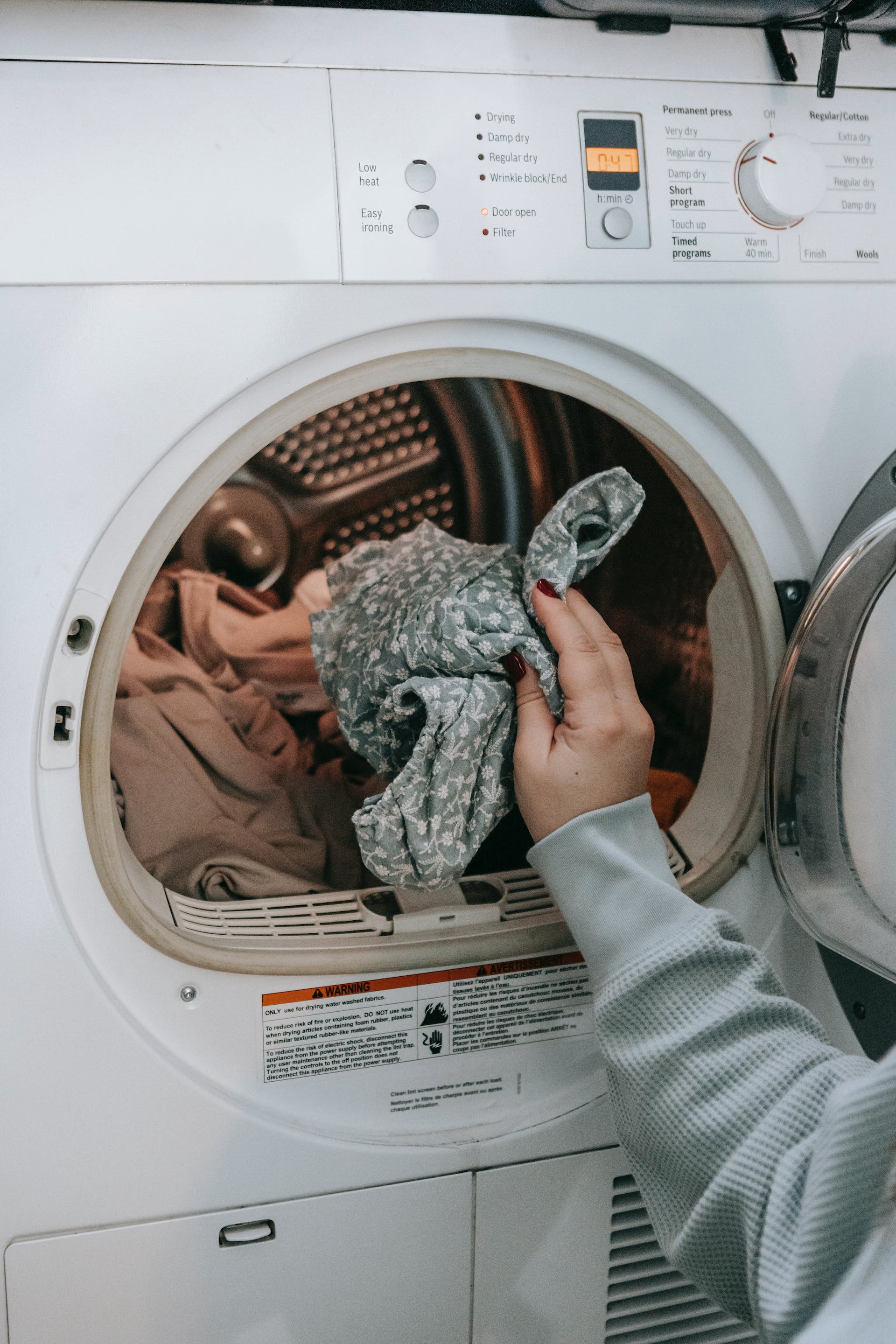 Person putting clothes into a washing machine | Source: Pexels