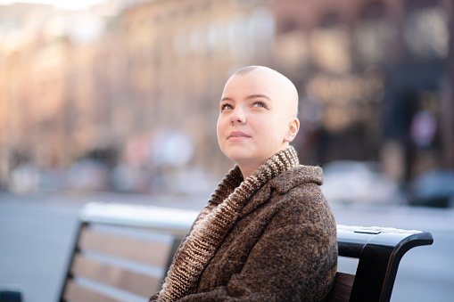 A cancer patient sits on a park bench while looking up into the sky | Photo: Getty Images