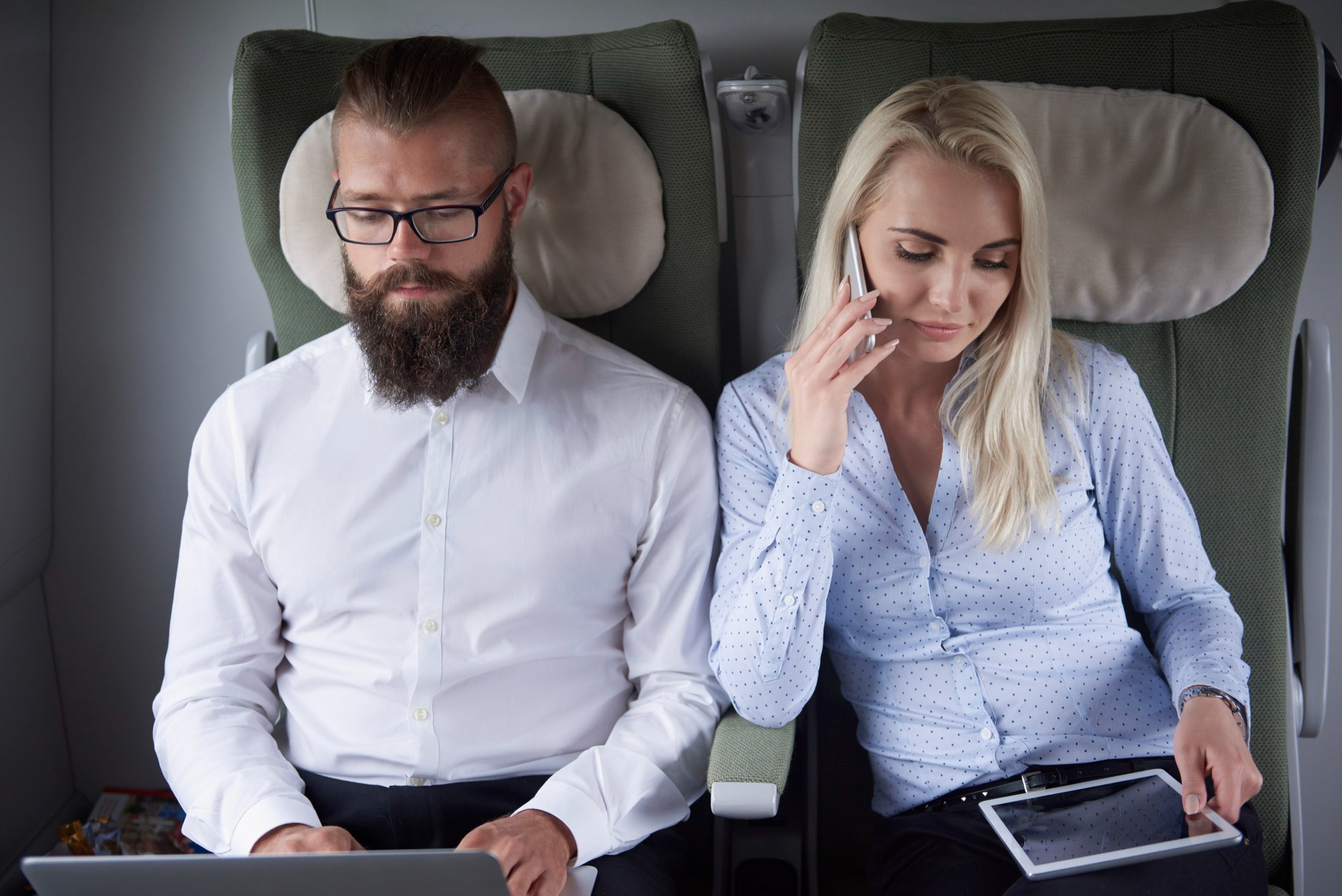 A woman on a phone seated next to a man on a plane | Source: Freepik