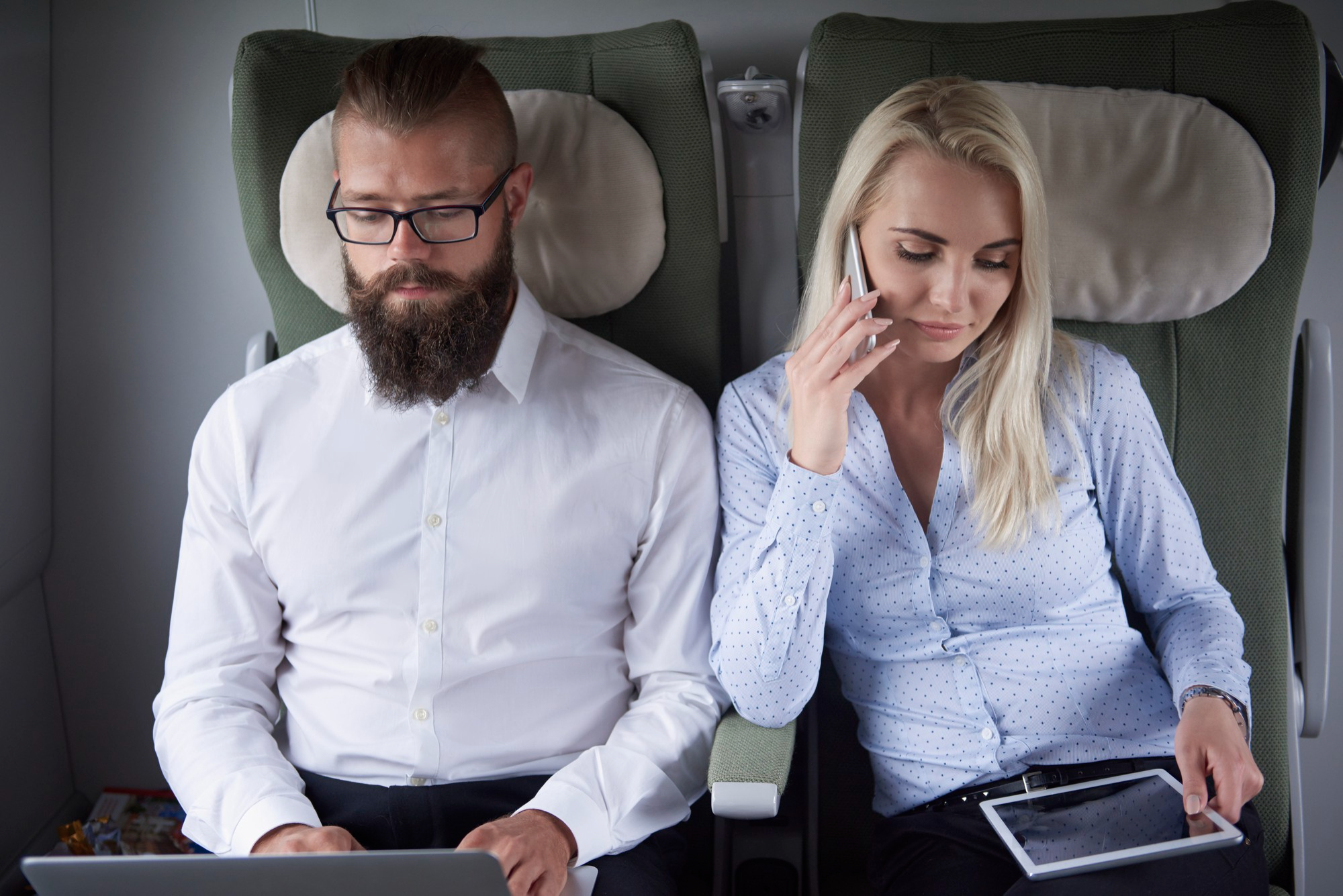 Una mujer hablando por teléfono sentada junto a un hombre en un avión | Fuente: Freepik