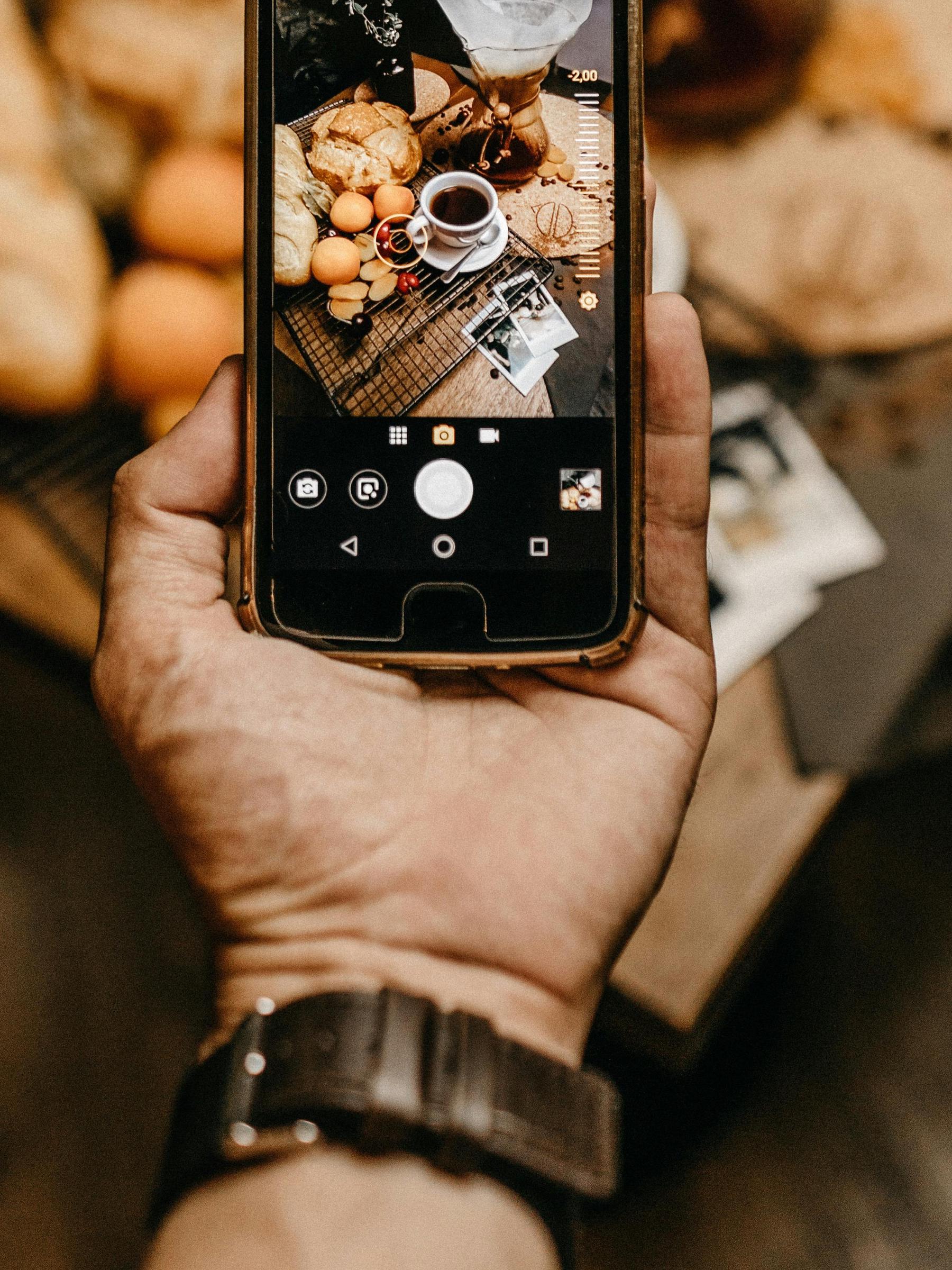 A man holds a cell phone with a picture of food preparation displayed | Source: Pexels