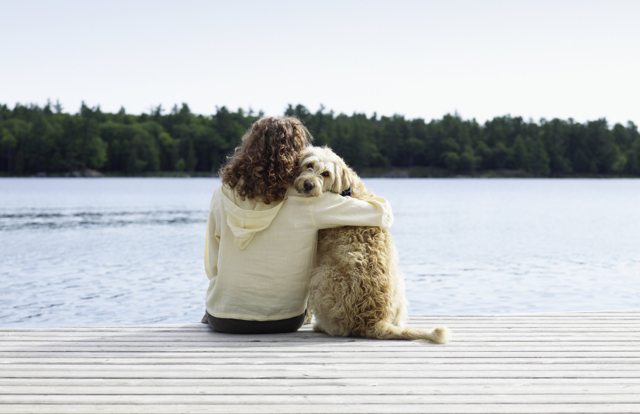 Frau sitzt mit Hund auf Steg I Quelle: Getty Images