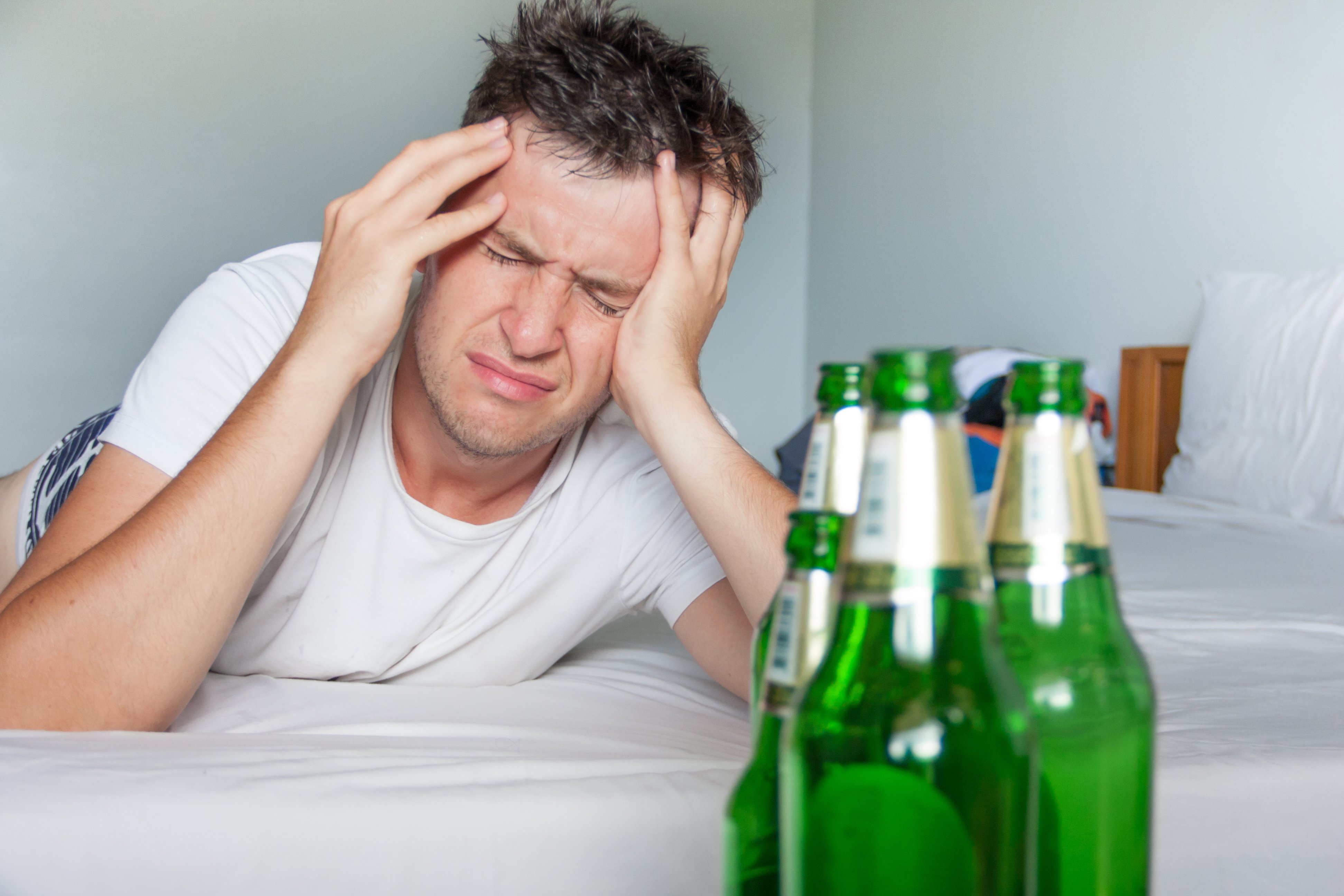 Man suffering from a hangover while holding his aching head | Photo: Shutterstock/Michael Traitov